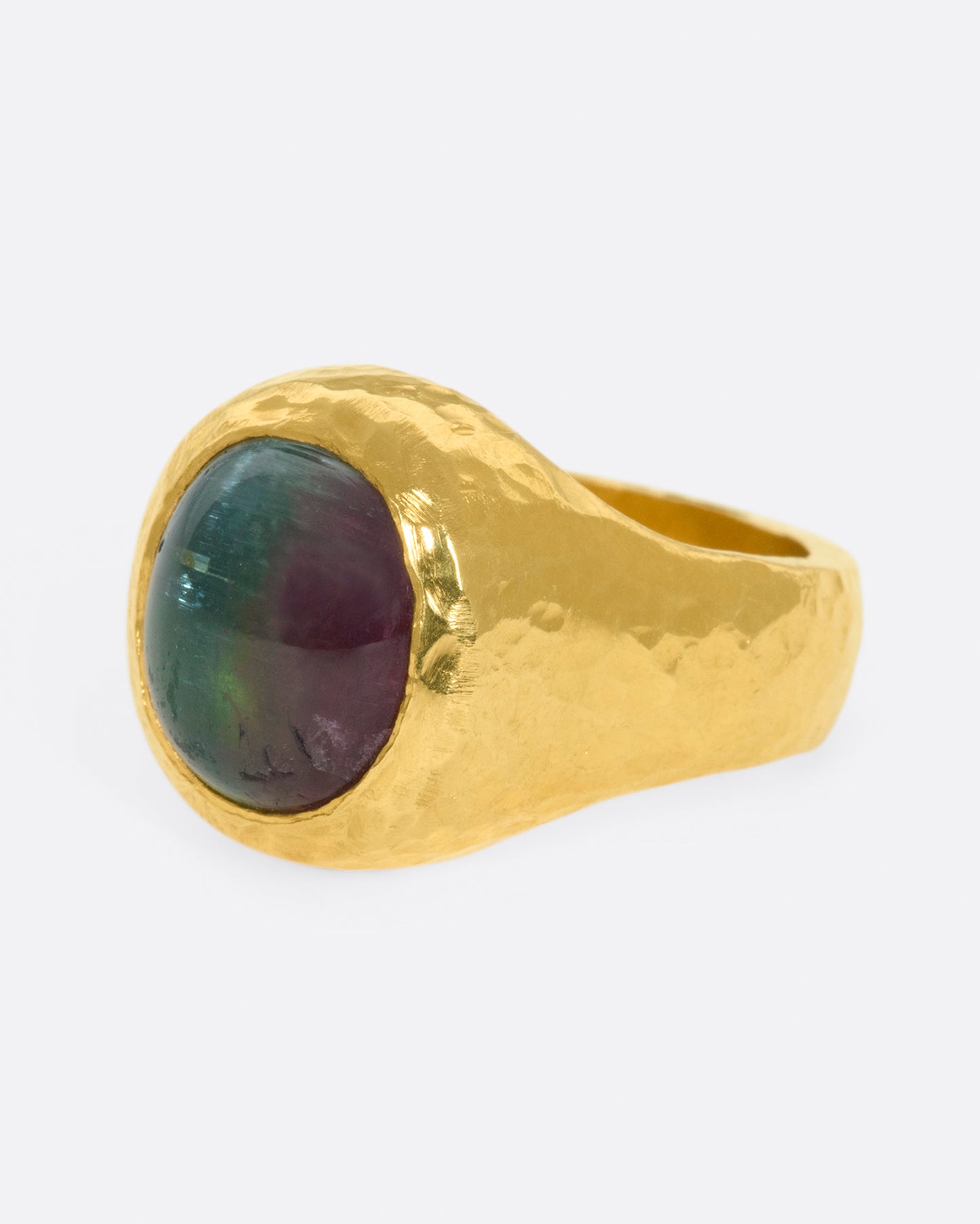A bicolor pink and green tourmaline sits at the center of this heavy, hammered, high karat gold ring.