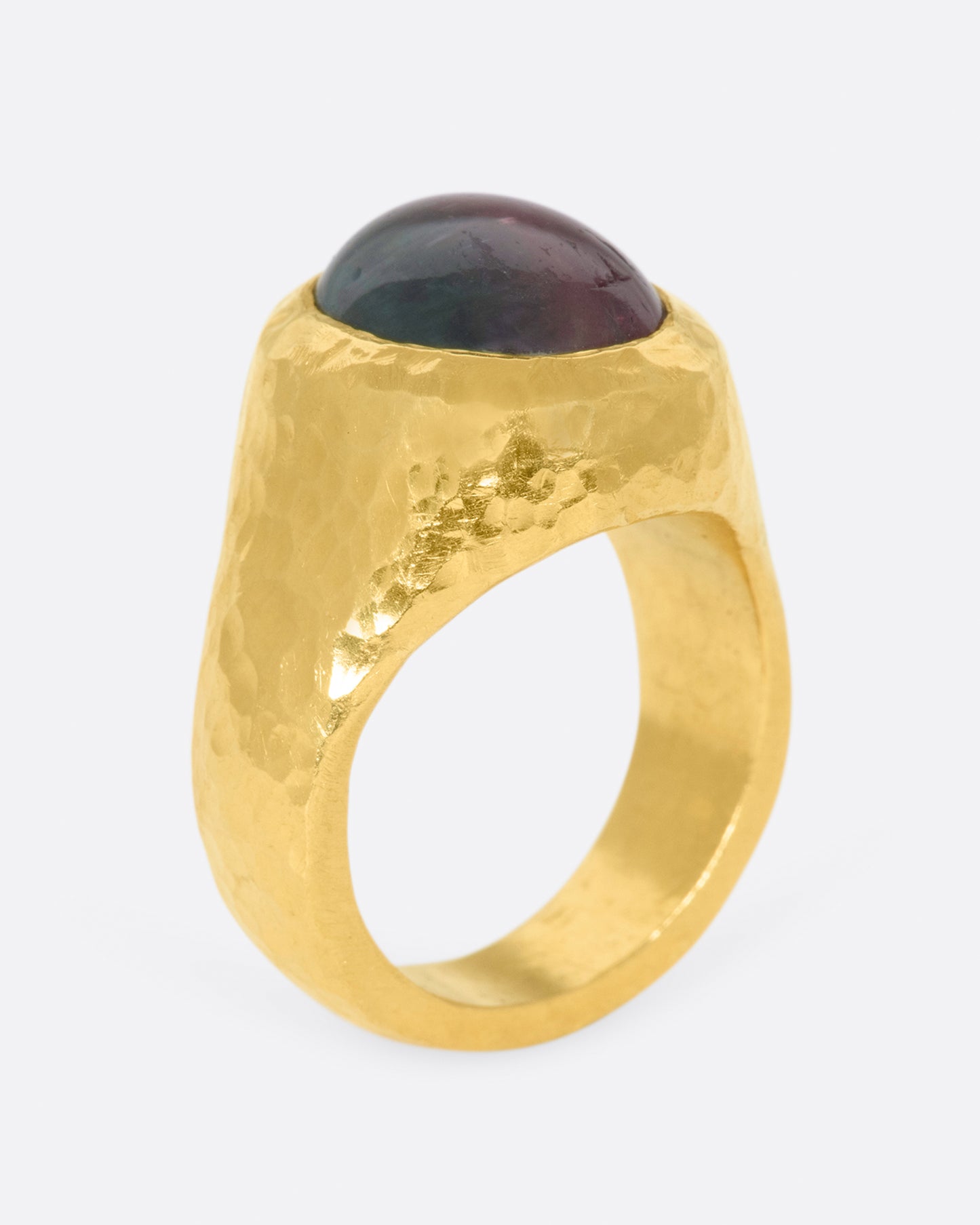 A bicolor pink and green tourmaline sits at the center of this heavy, hammered, high karat gold ring.