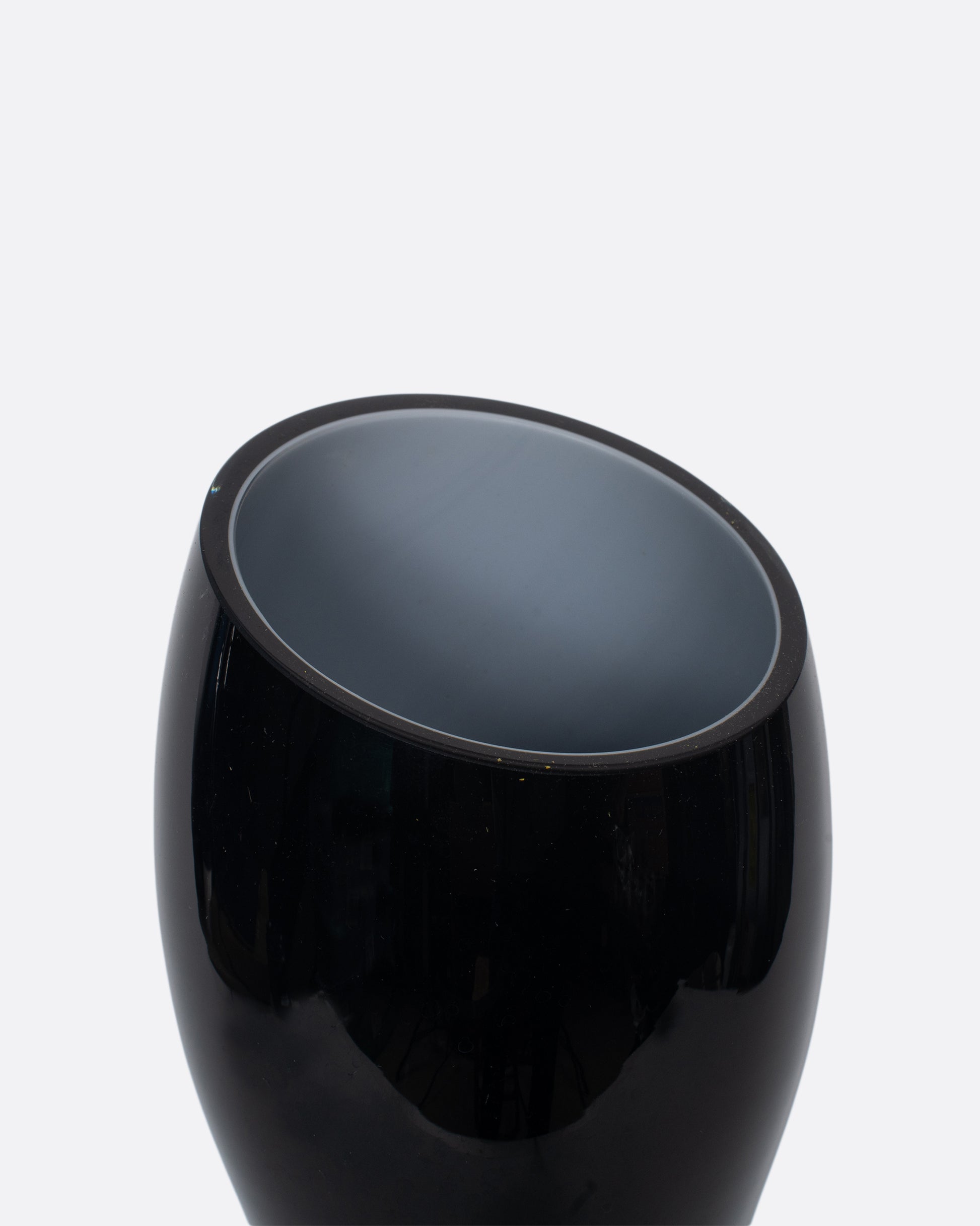 A bold, black cased glass vase with an hourglass figure and a cut slanted top.