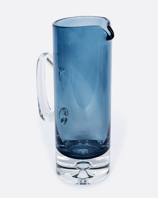This vintage blue glass pitcher is made of mouth-blown glass and hand-polished block crystal, giving it a heavy weight