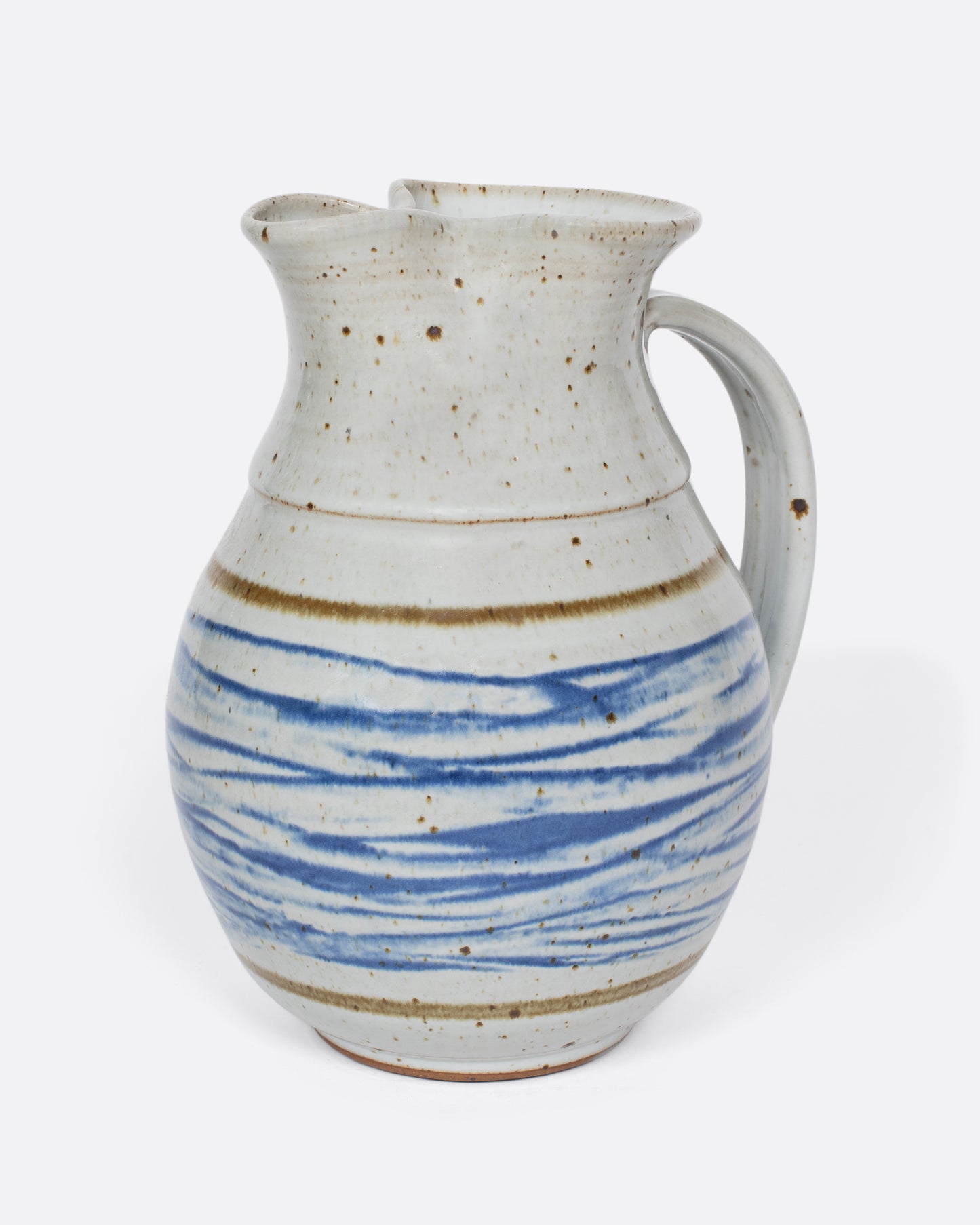 This vintage studio-made ceramic pitcher features a speckled white glaze and a blue water-like, hand-painted pattern.