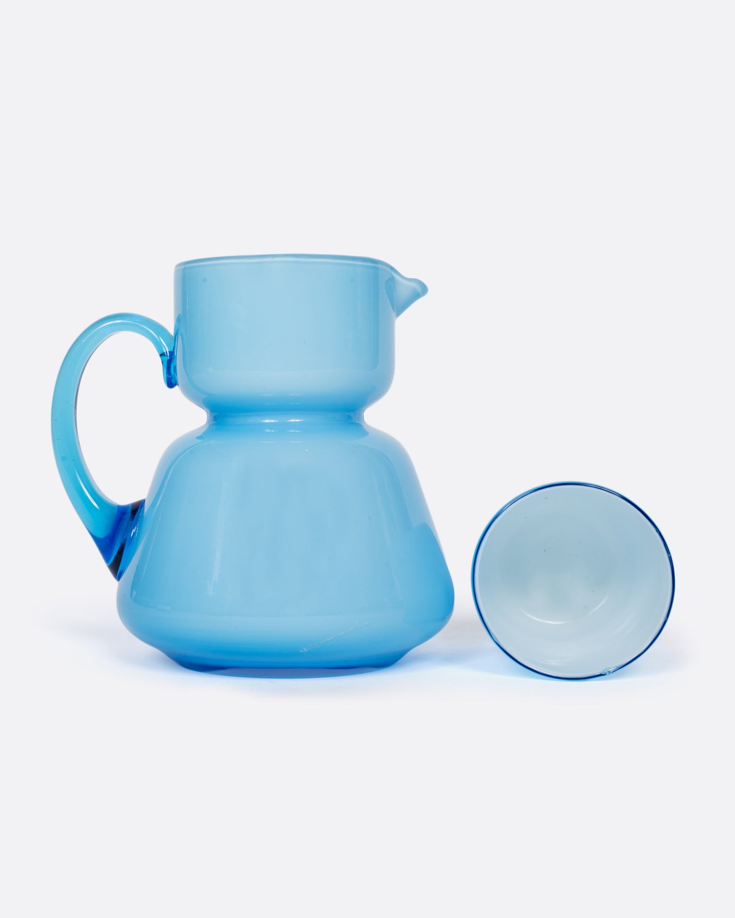 A vintage cased glass cup and creamer with an hourglass shape. Cased glass is made with a layer of white glass underneath creating the velvety, light blue hue.