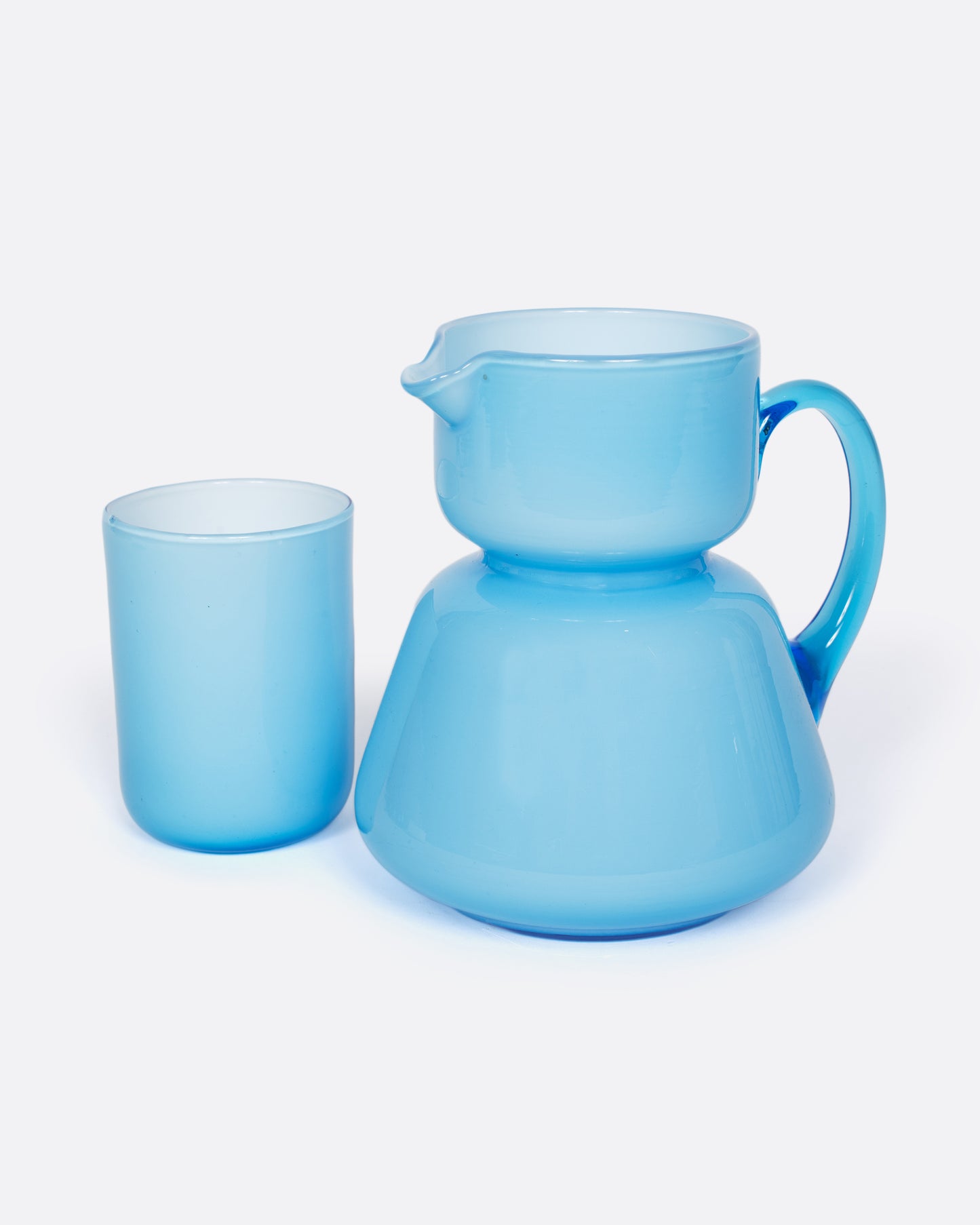 A vintage cased glass cup and creamer with an hourglass shape. Cased glass is made with a layer of white glass underneath creating the velvety, light blue hue.