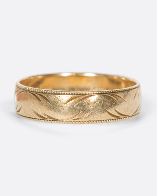 A vintage yellow gold band ring with milgrain edges and semi circular carvings throughout