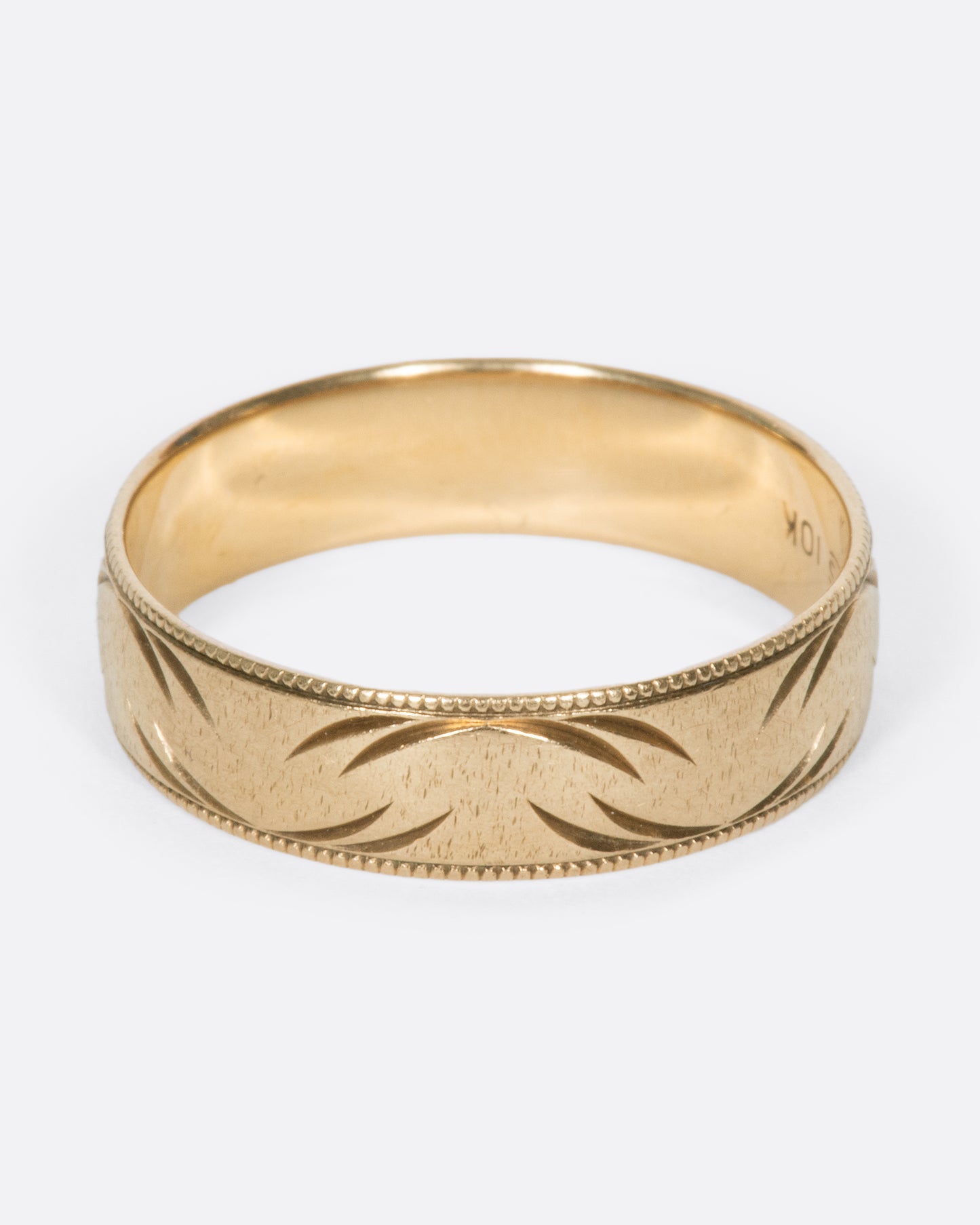 A vintage yellow gold band ring with milgrain edges and semi circular carvings throughout