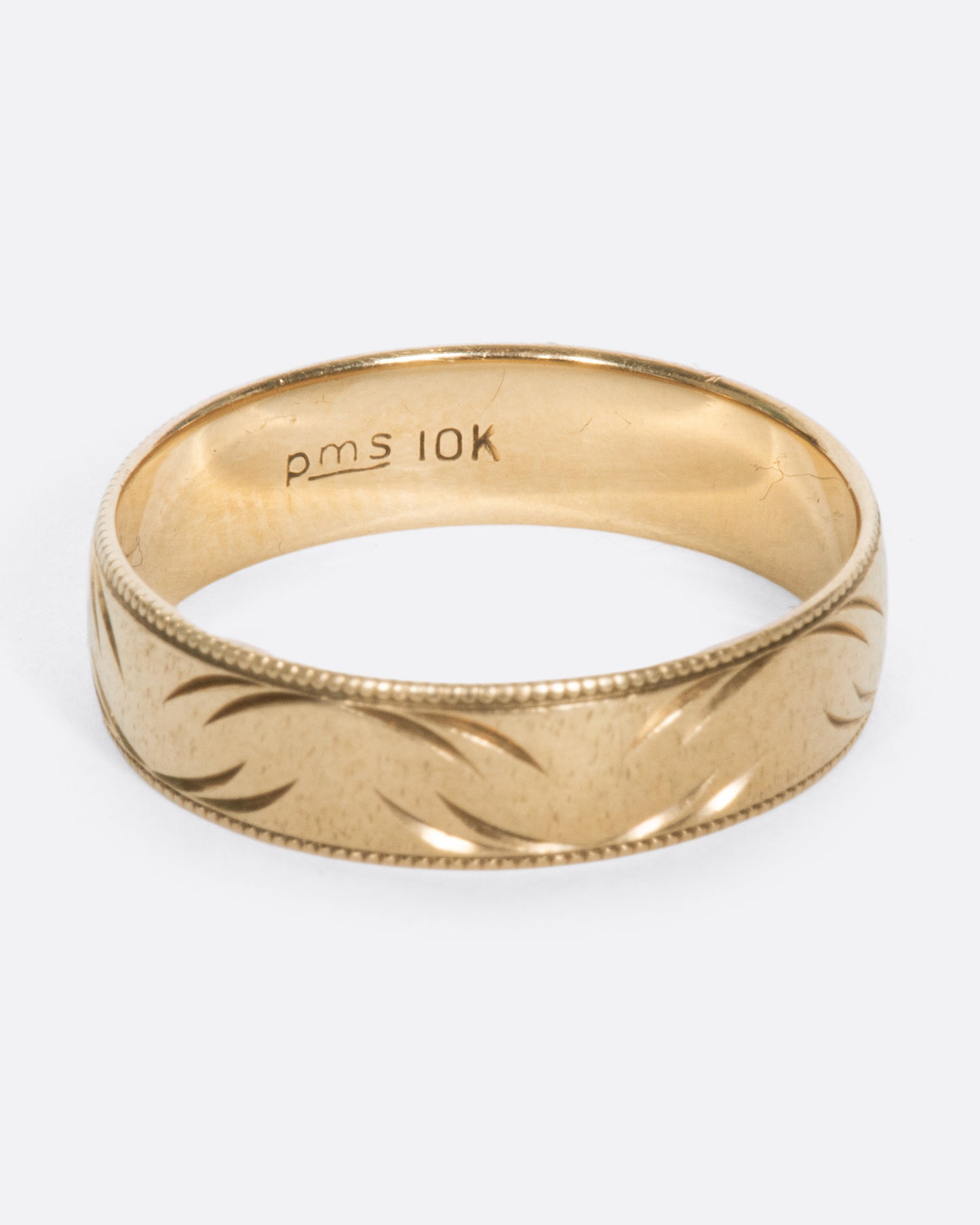 A vintage yellow gold band ring with milgrain edges and semi circular carvings throughout