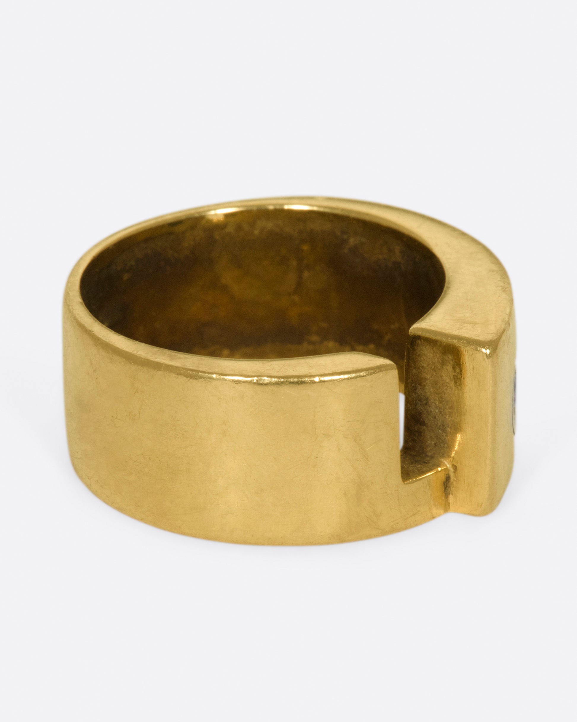 A gold band with a round diamond and rectangular cutout.