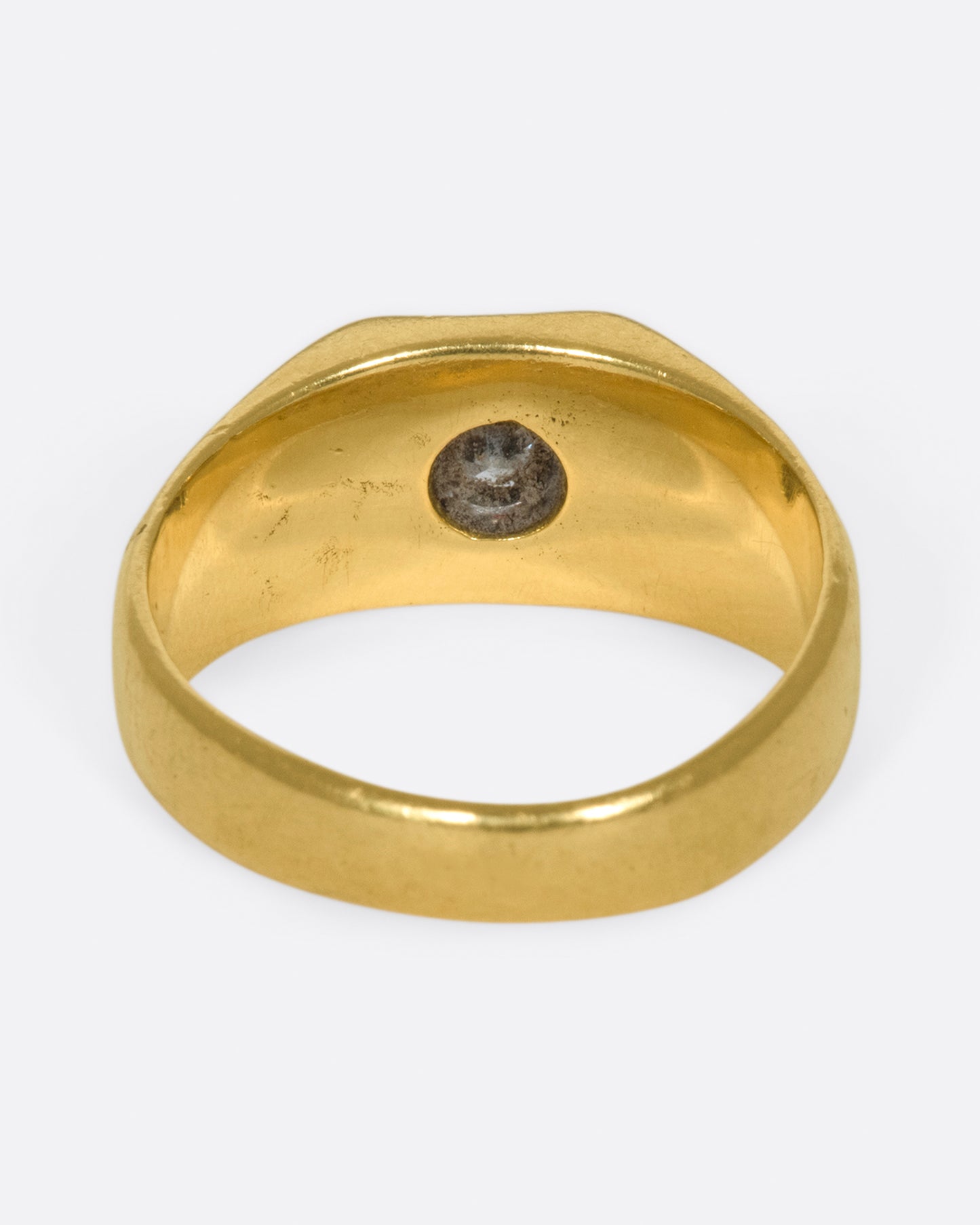 A vintage gold signet ring with a sunken diamond at its center.
