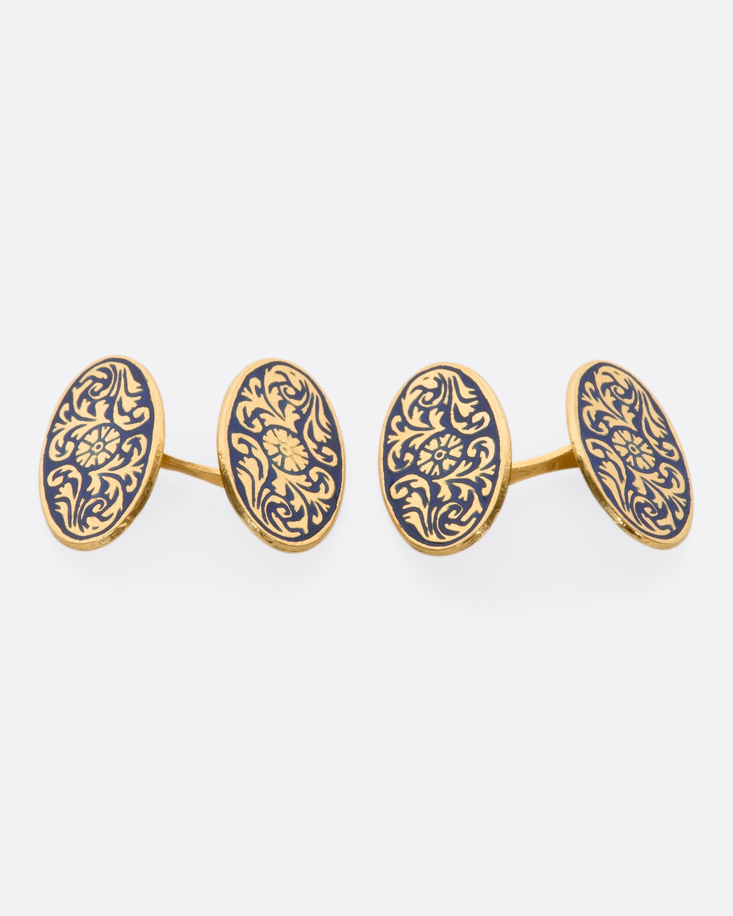 A pair of solid gold vintage cufflinks with intricate flourishes and contrasting dark blue enamel.