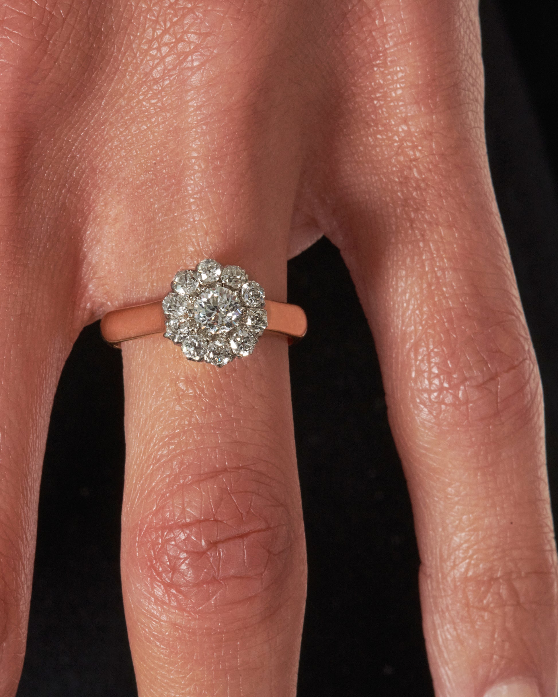 A wide yellow gold band with an old European cut diamond at its center, surrounded by a halo of smaller diamonds.