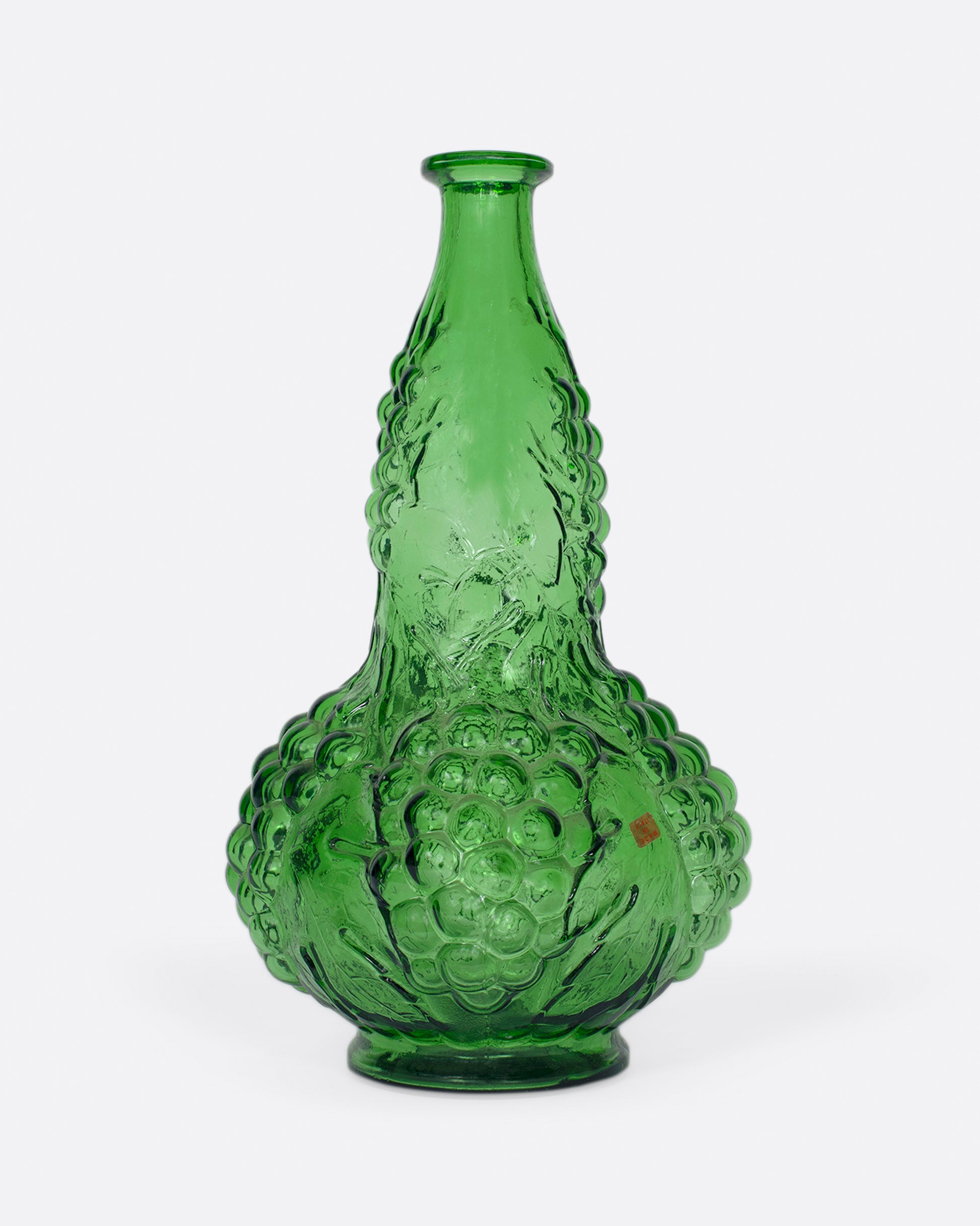 A tall, bottle green glass decanter with a textured stopper.