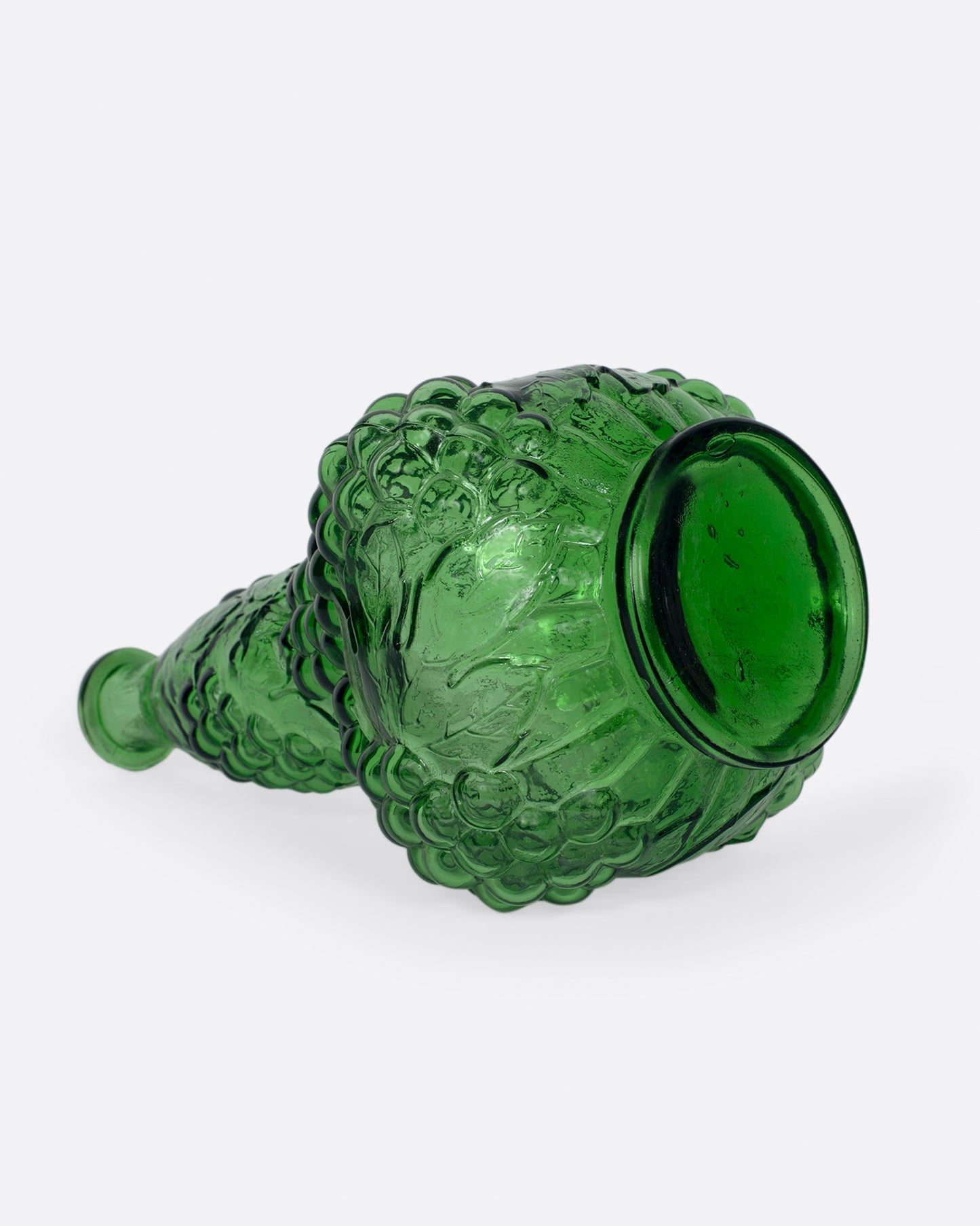 A tall, bottle green glass decanter with a textured stopper.
