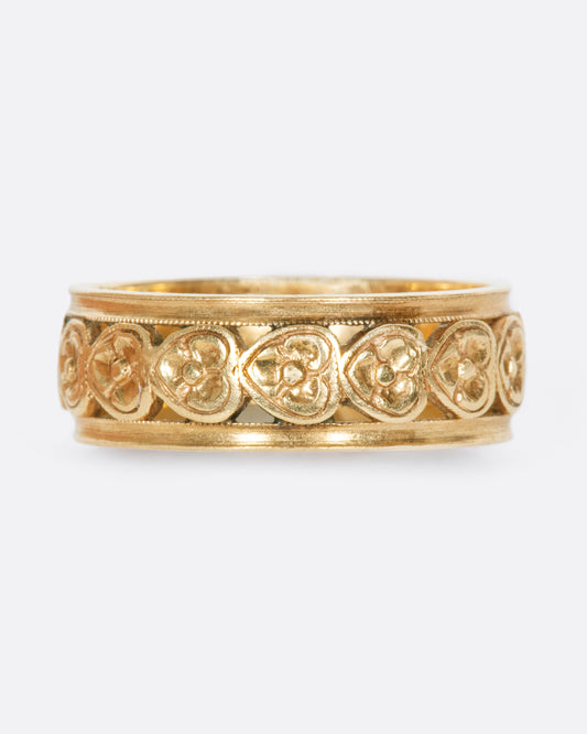 A yellow gold band ring lined with sideways hearts.