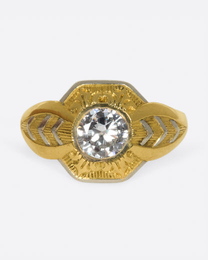 Vintage ring in yellow gold and platinum, a round diamond in a hexagonal platinum setting with engraved gold and chevron shoulders