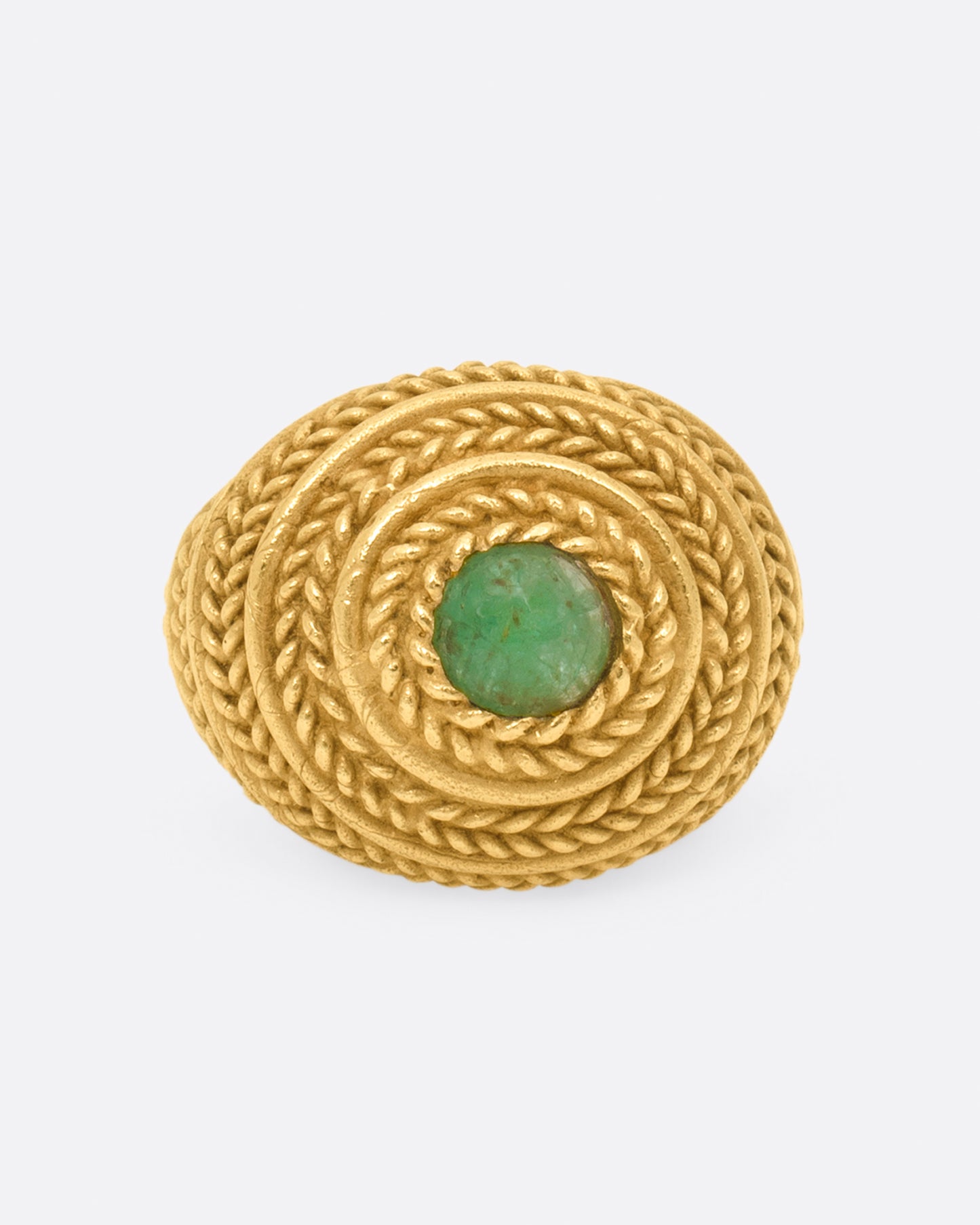 A dome ring covered in braided texture with an emerald cabochon at its peak.