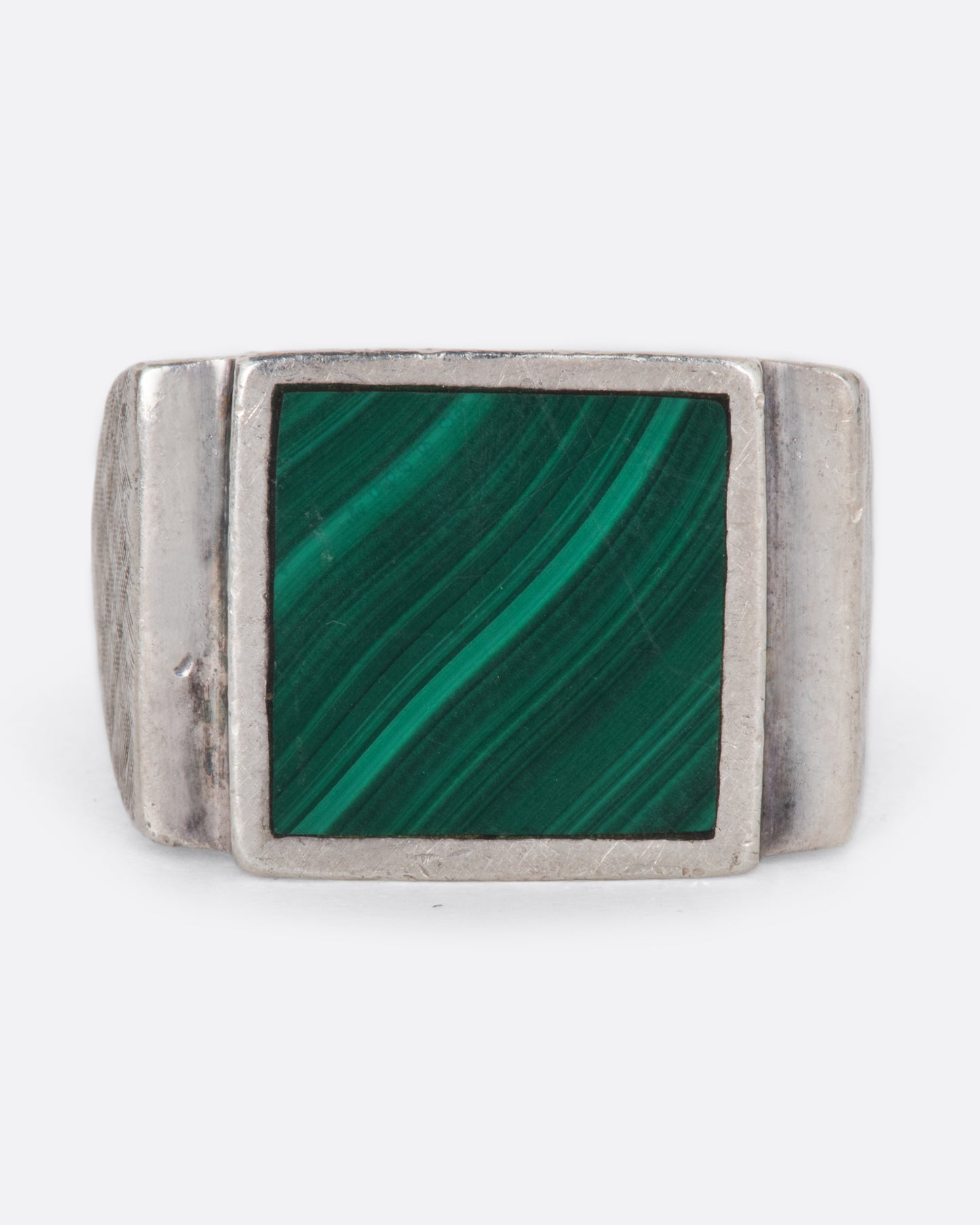 A vintage sterling silver signet ring with a large square malachite at its center, stepped sides, and a wide textured band.