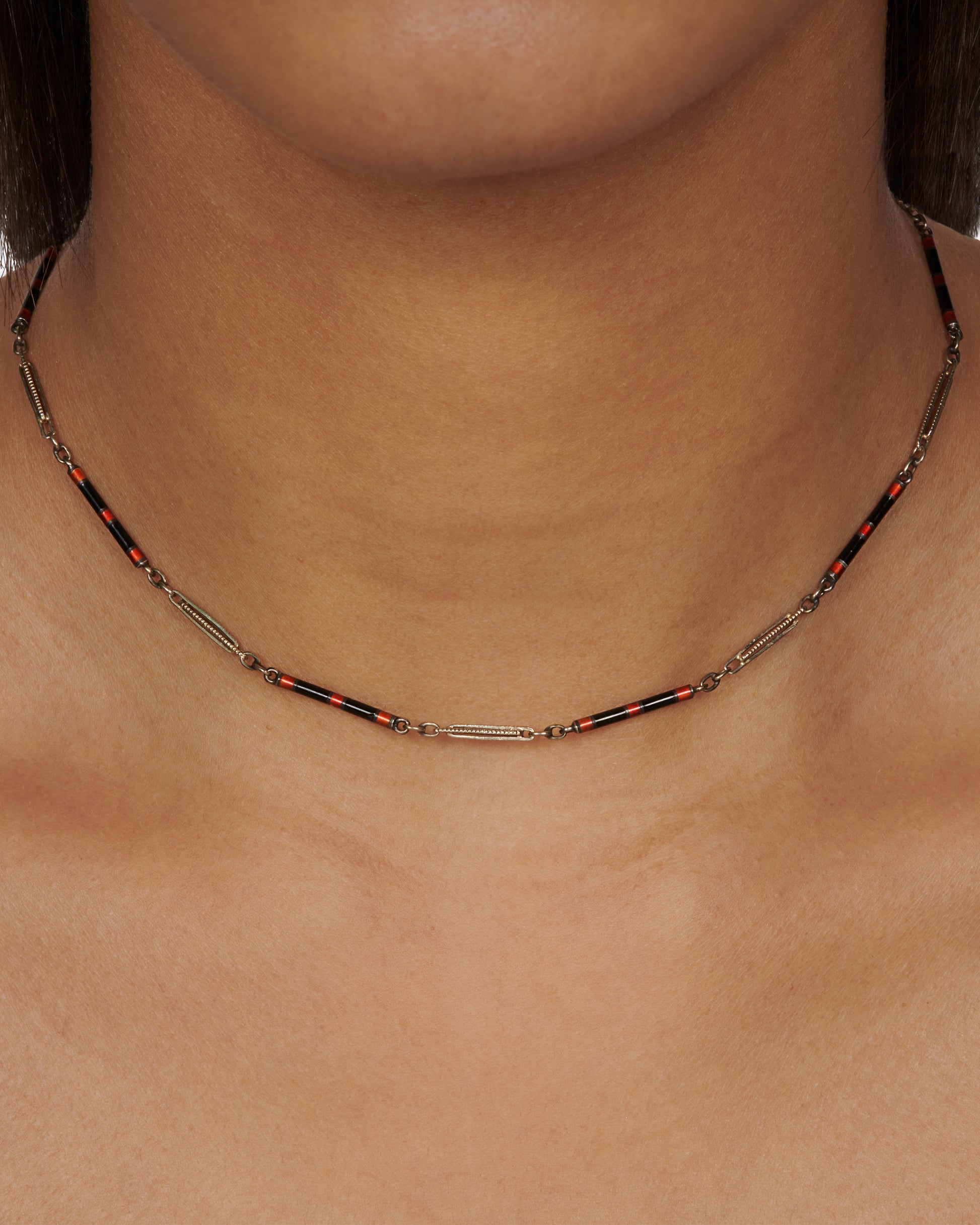 A vintage white gold bar-link chain necklace dotted with red and black enamel—a subtle pop of color for someone with a minimalist sensibility.