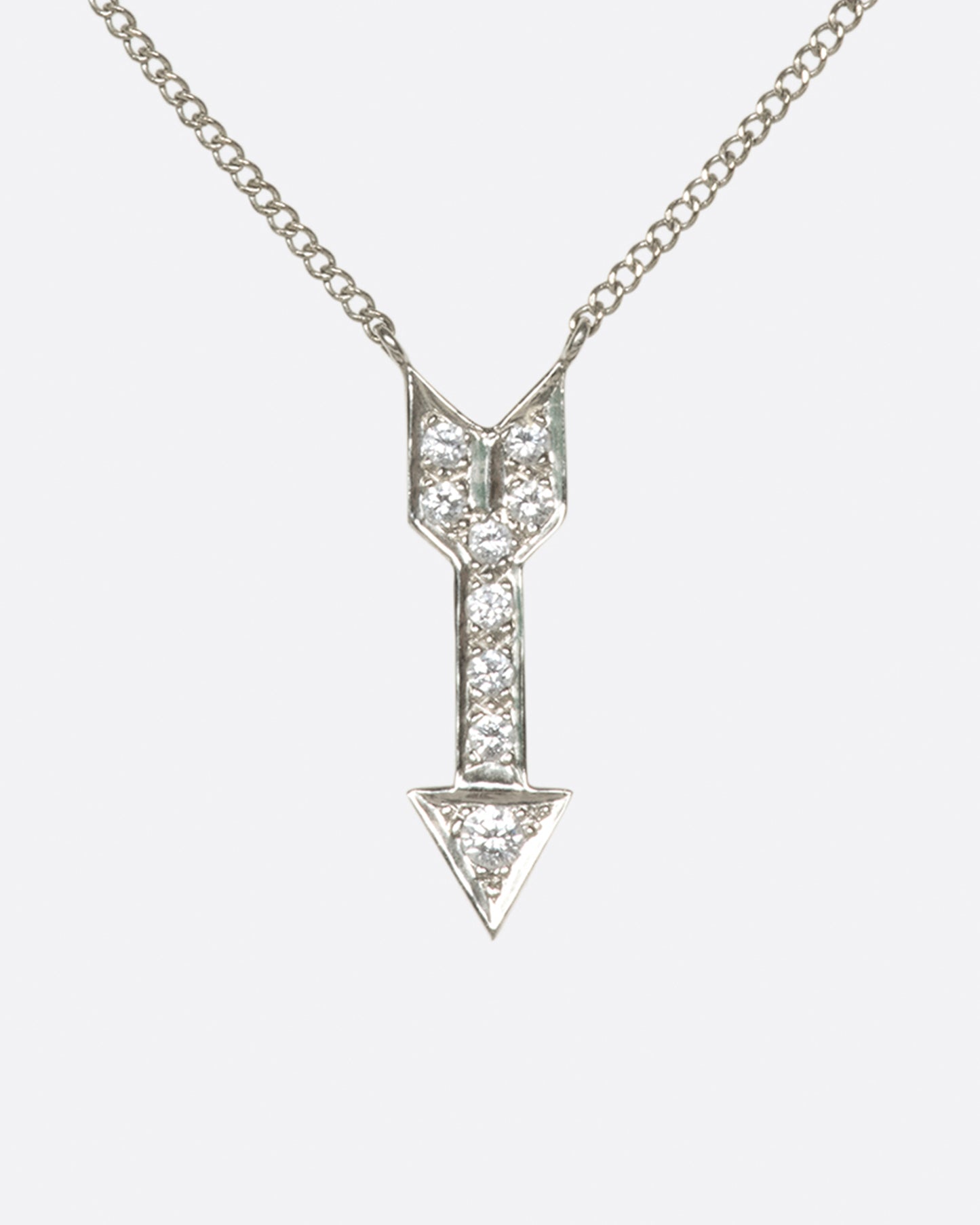 A narrow curb chain is fixed directly to either side of this diamond-lined pendant.