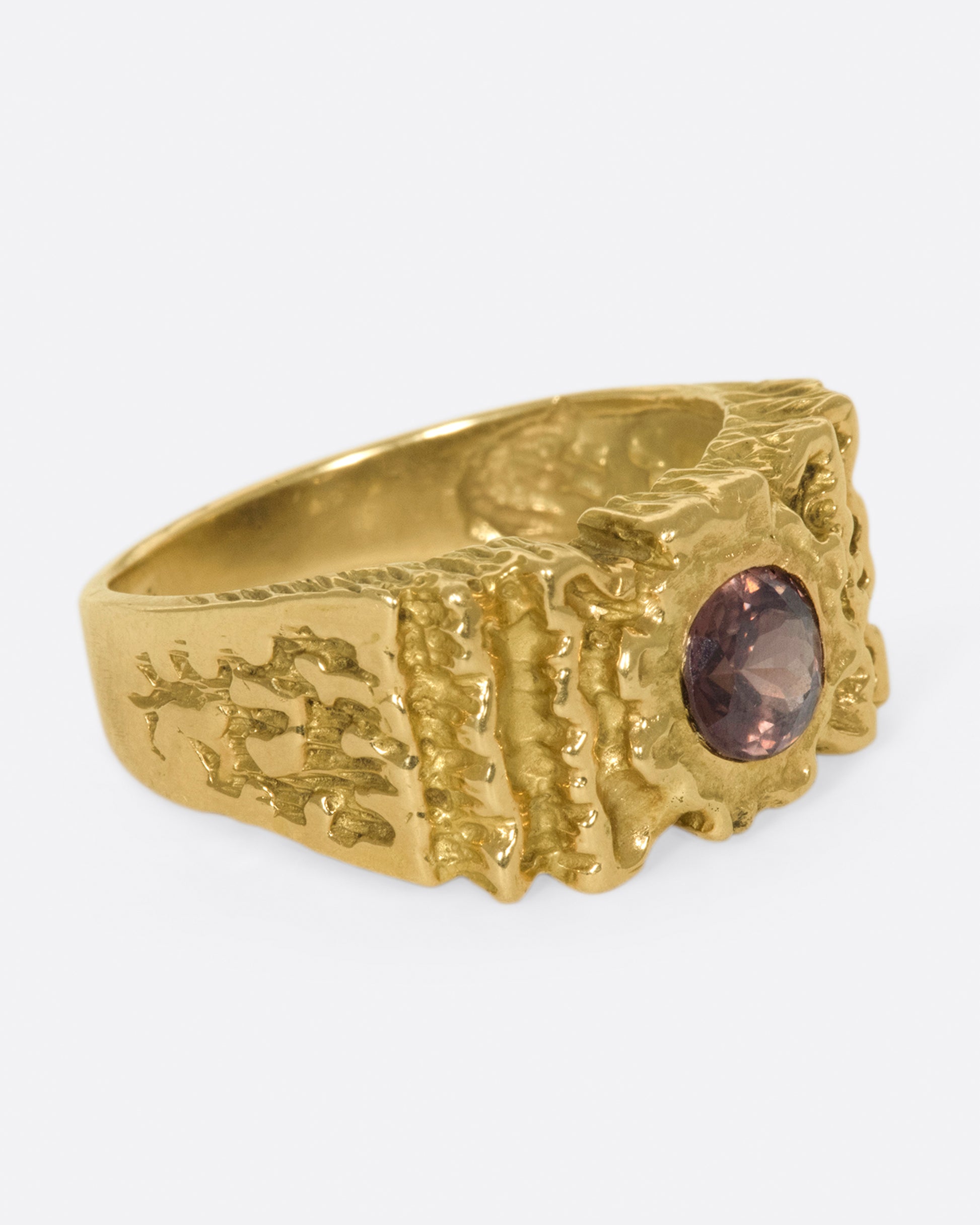 A right side view of a yellow gold ring with ribbon texture and round pink spinel.