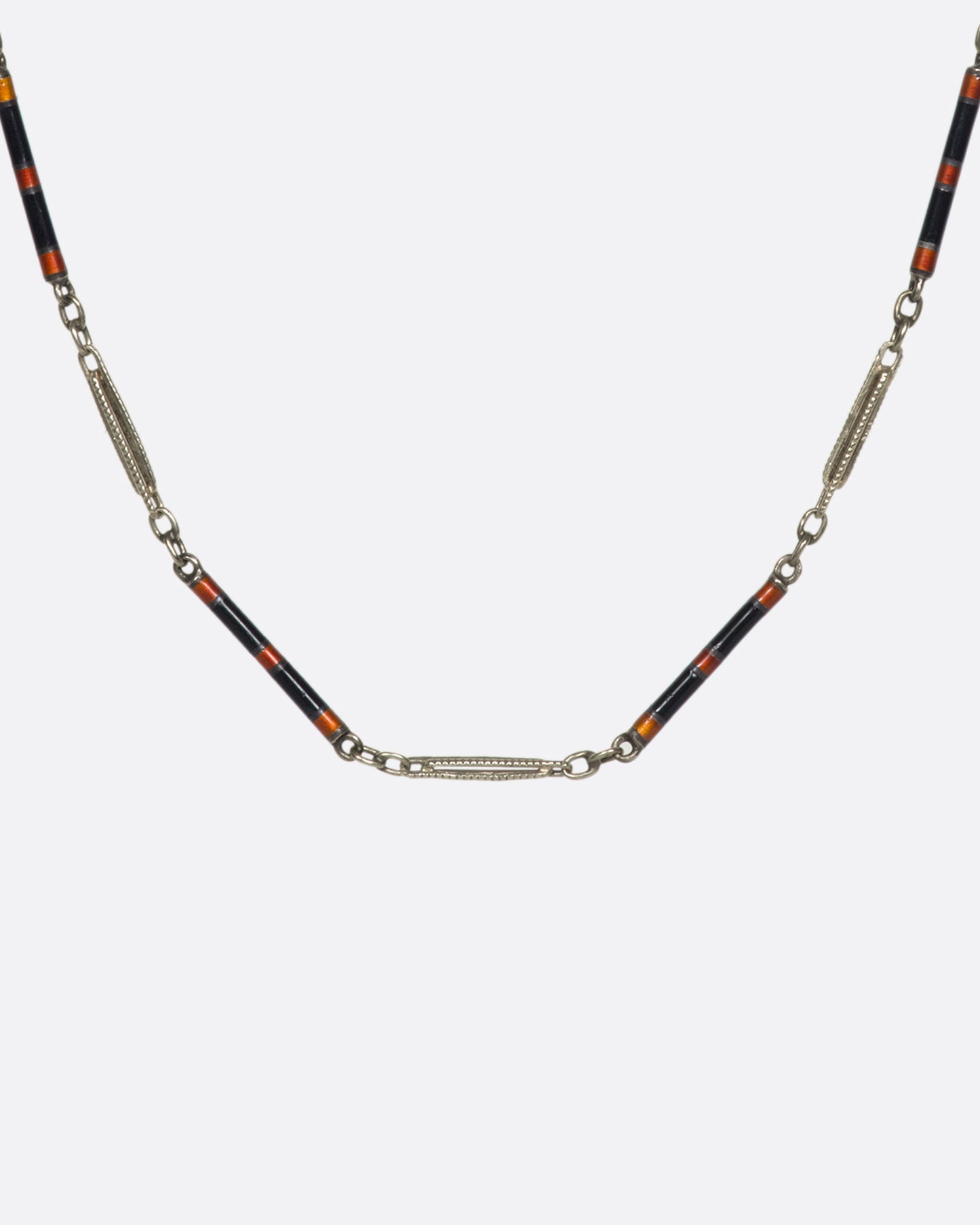 A vintage white gold bar-link chain necklace dotted with red and black enamel—a subtle pop of color for someone with a minimalist sensibility.