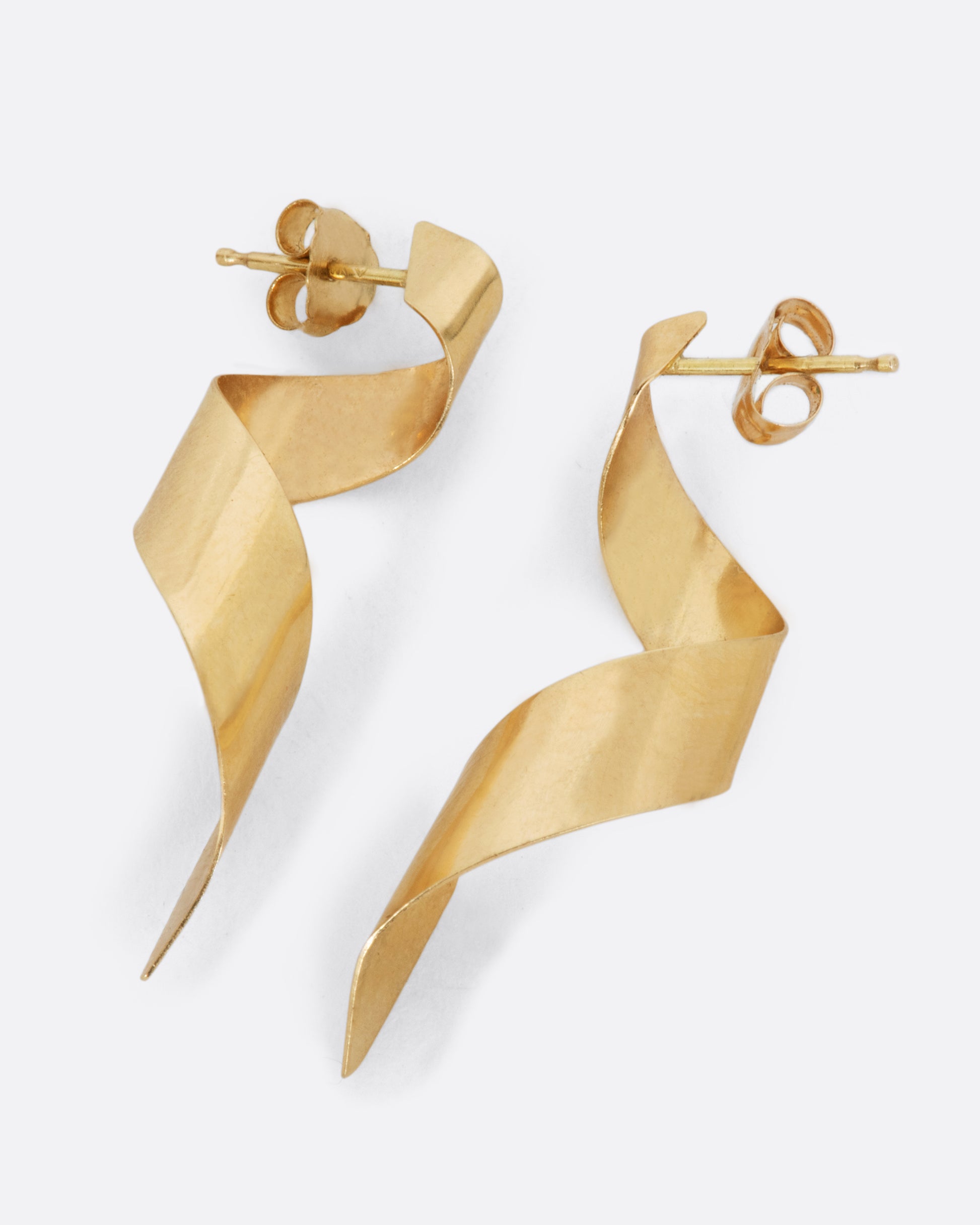 A pair of drop earrings made from 3D swirled gold ribbons. Shown from the side.