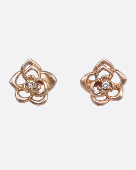 A pair of rose gold flower stud earrings with cutout petals and diamond centers.