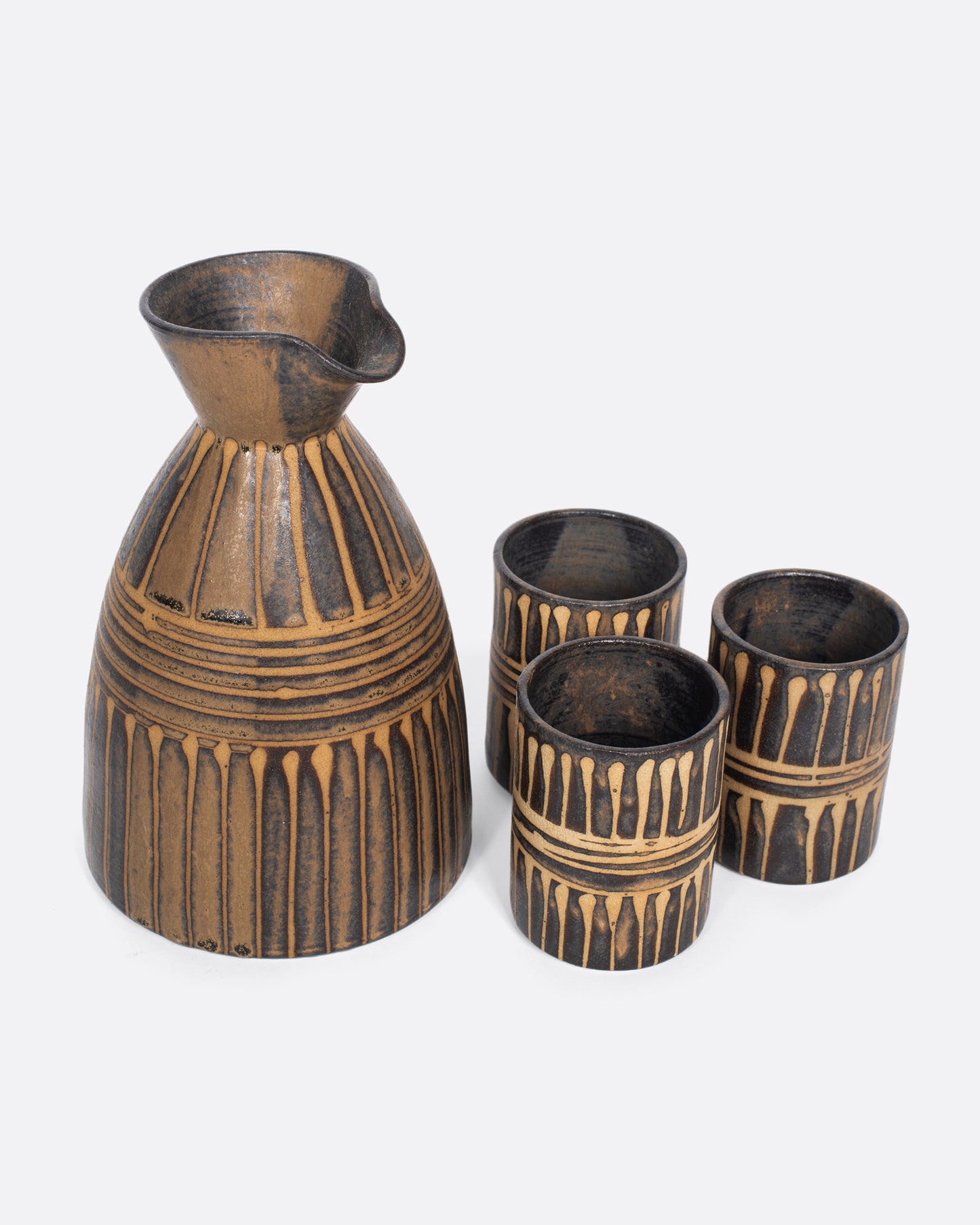 This vintage ceramic sake decanter set includes three cups, all with a matching incised light brown glaze, that creates a rich, textured look.