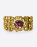 A front view of a yellow gold ring with ribbon texture and round pink spinel.