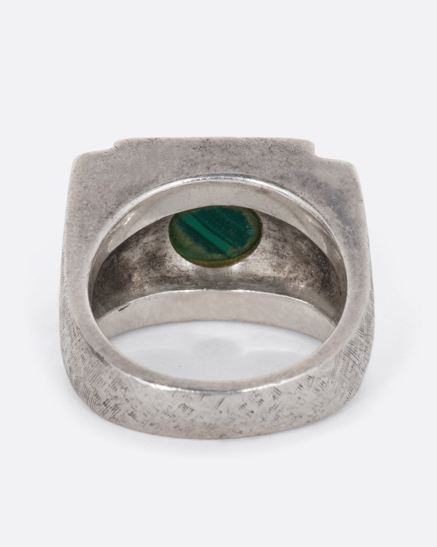 A vintage sterling silver signet ring with a large square malachite at its center, stepped sides, and a wide textured band. Shown from the back.