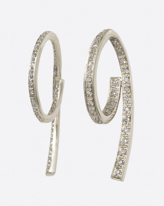 A pair of white gold, 3D loop de loop earrings, lined with diamonds.