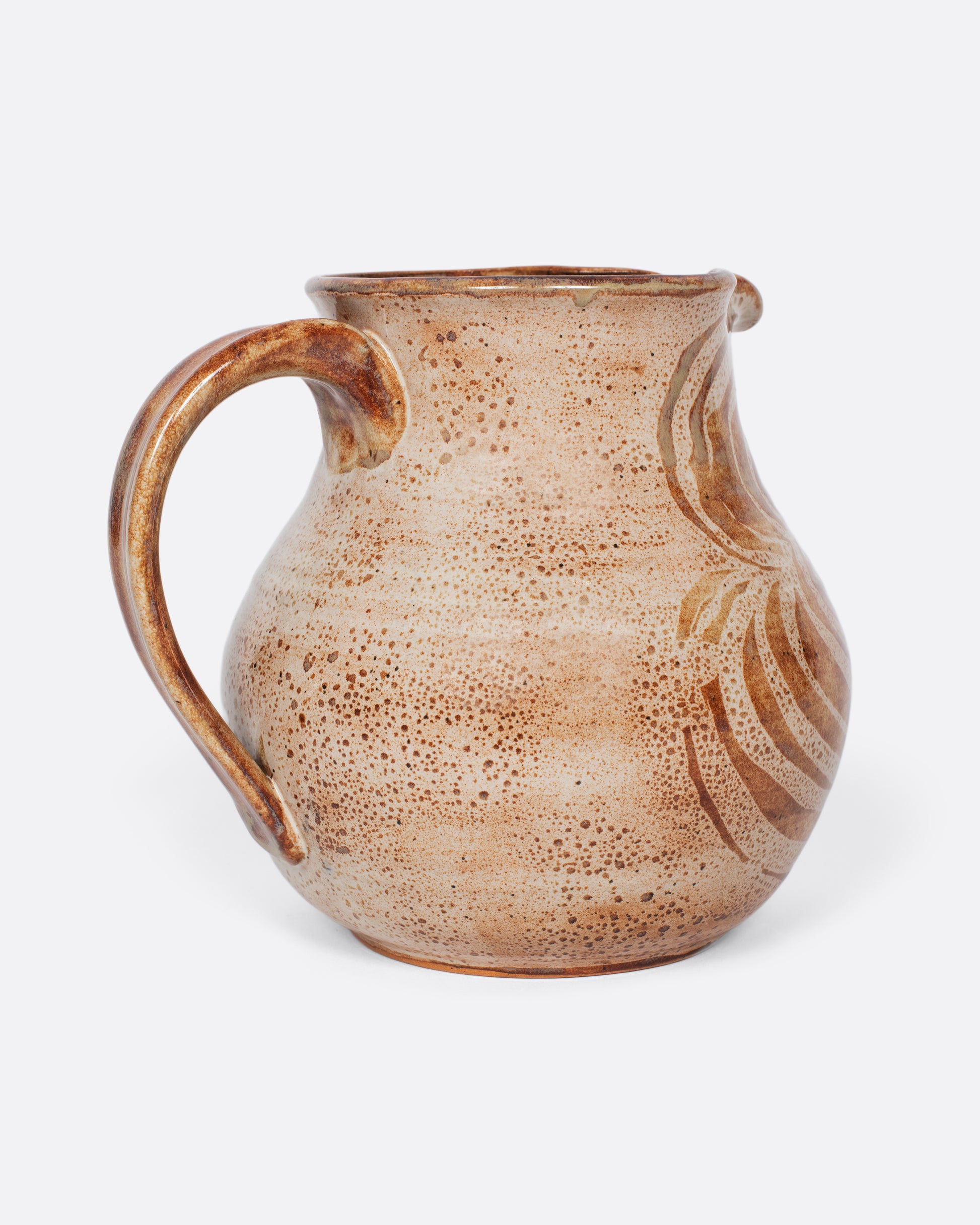 A studio-made, beautifully weighted, rounded ceramic pitcher with a brown swirl design that mimics a blossoming flower.