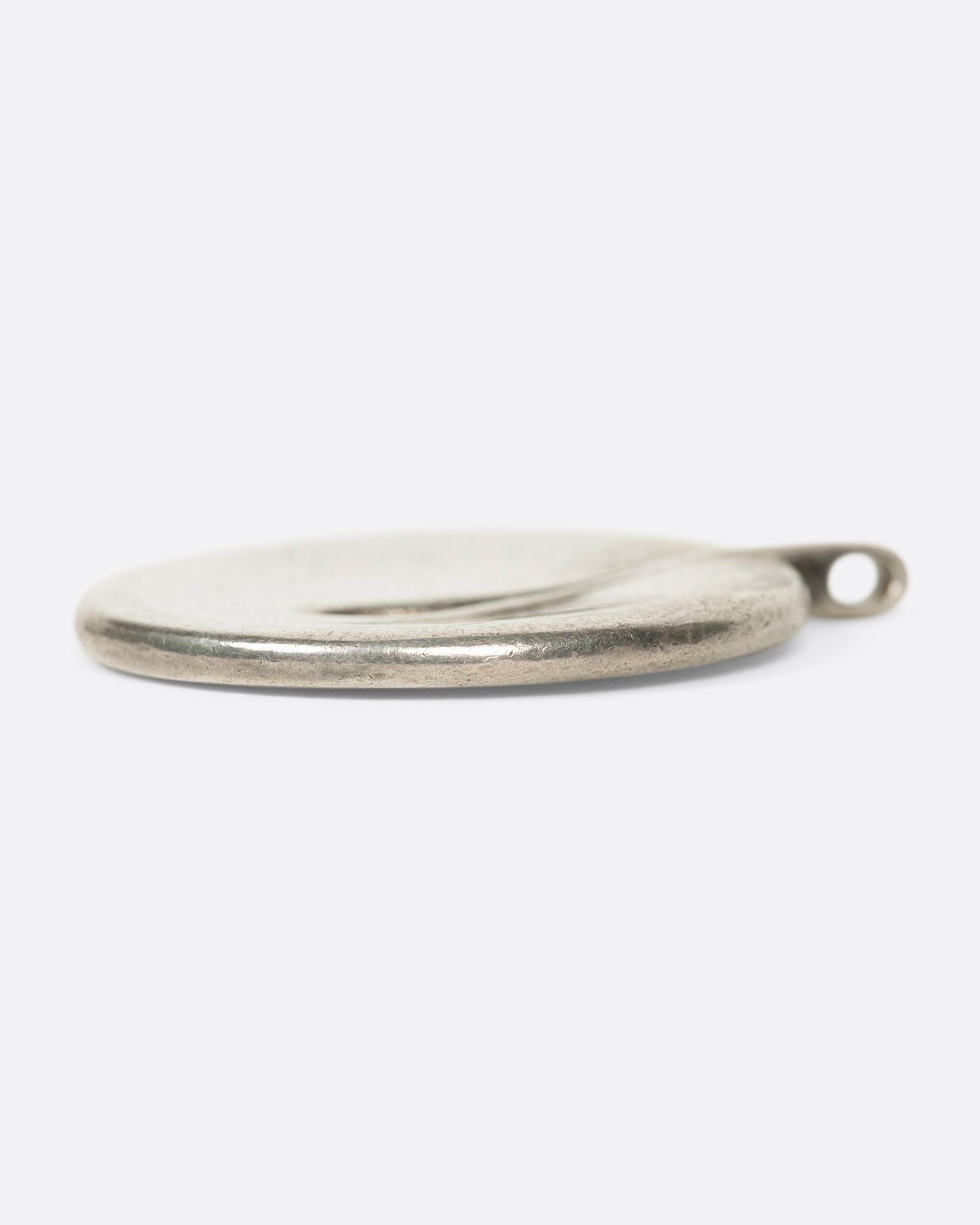 A vintage sterling silver circular pendant with a teardrop opening