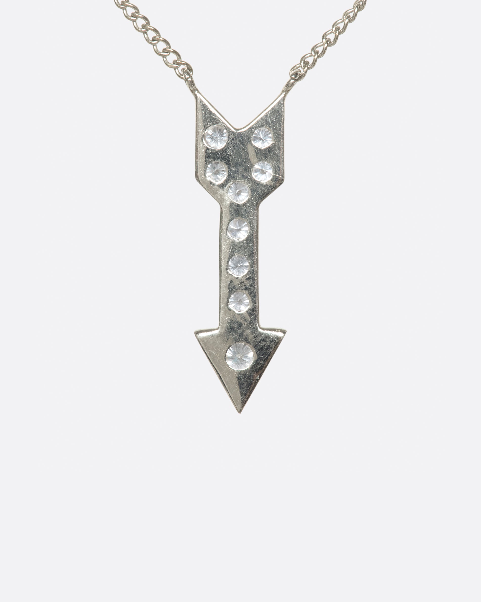 A narrow curb chain is fixed directly to either side of this diamond-lined pendant.