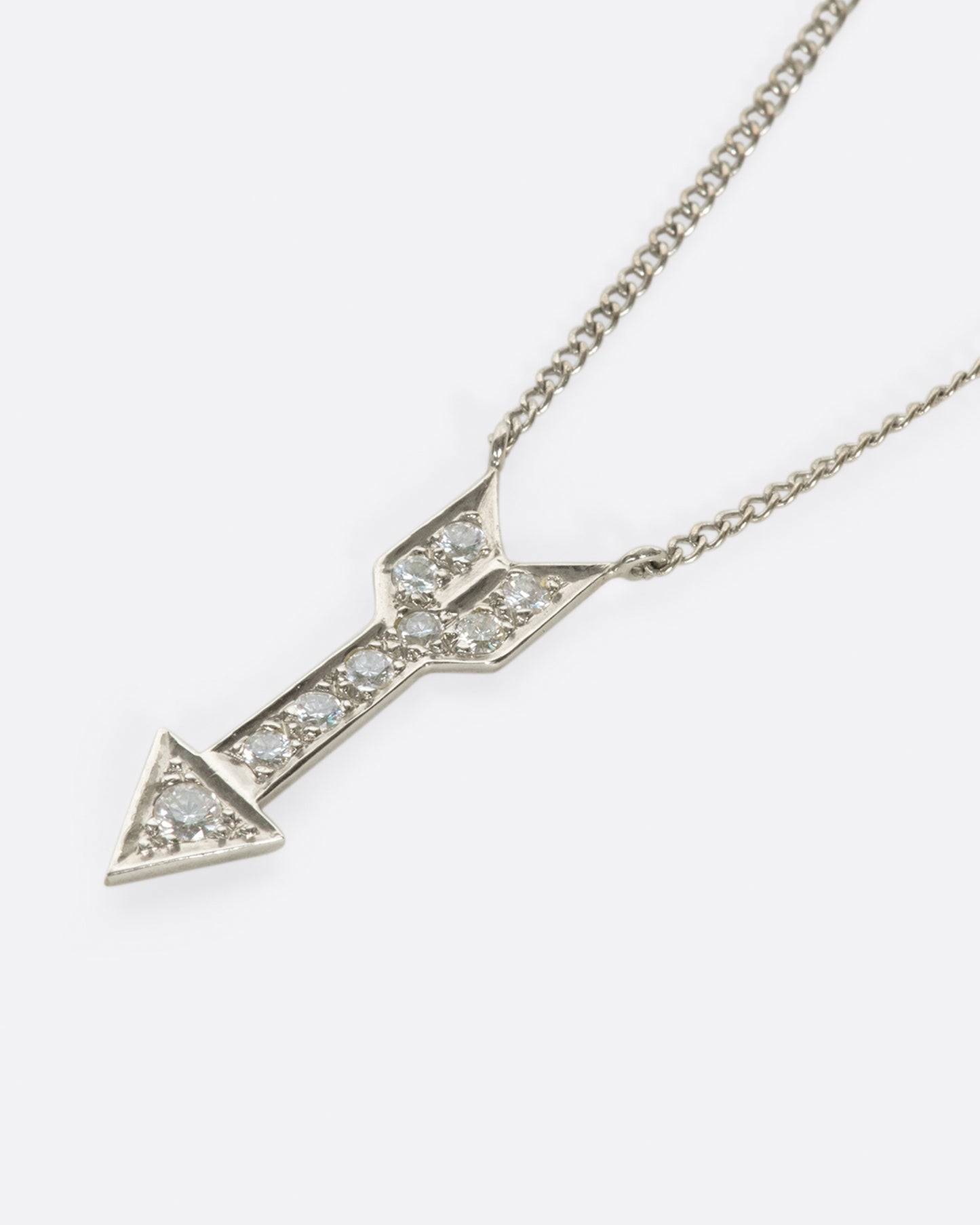 A narrow curb chain is fixed directly to either side of this diamond-lined pendant.