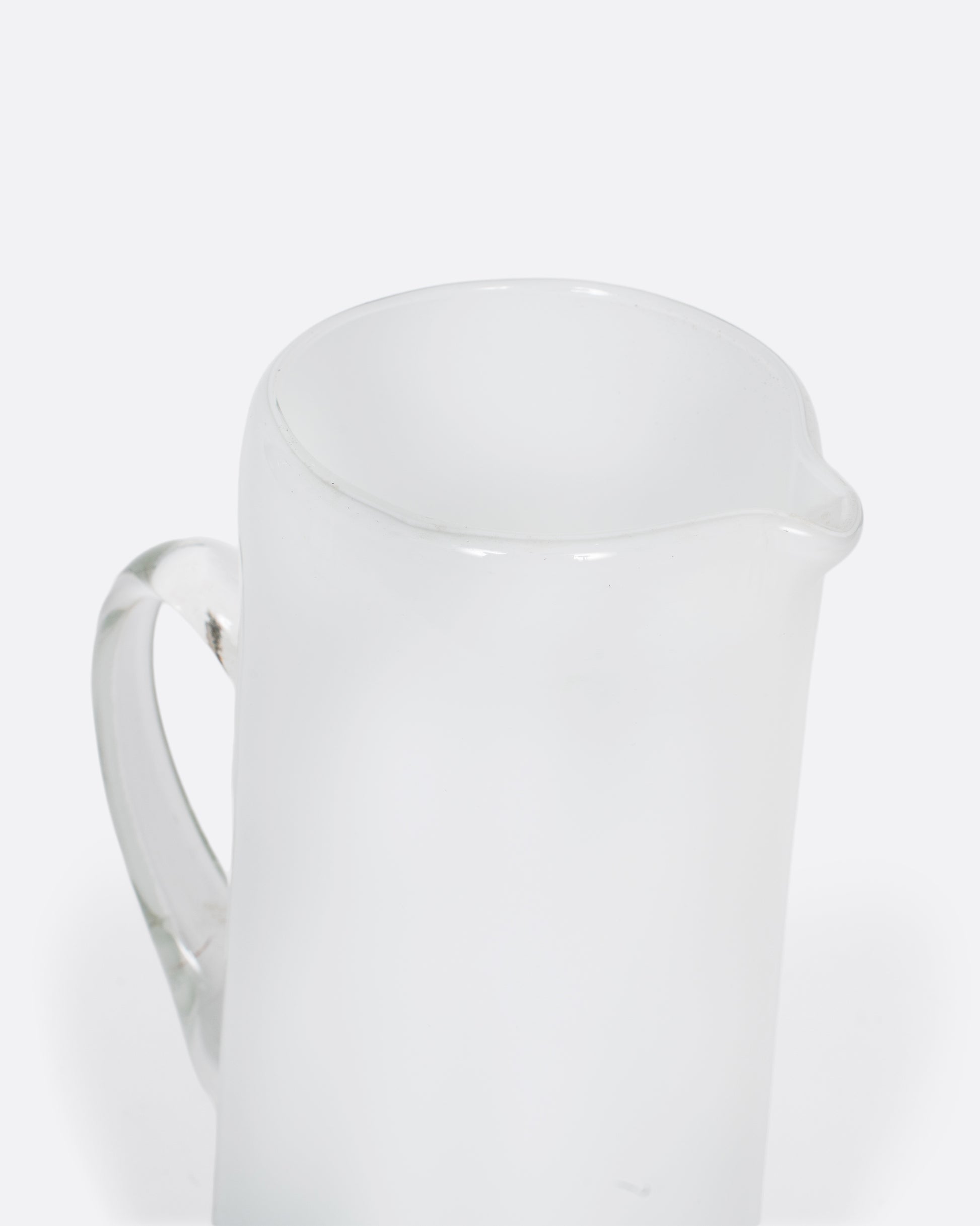 A vintage white cased glass pitcher. Two layers of white glass add depth to its color, creating an elegant, sleek look.