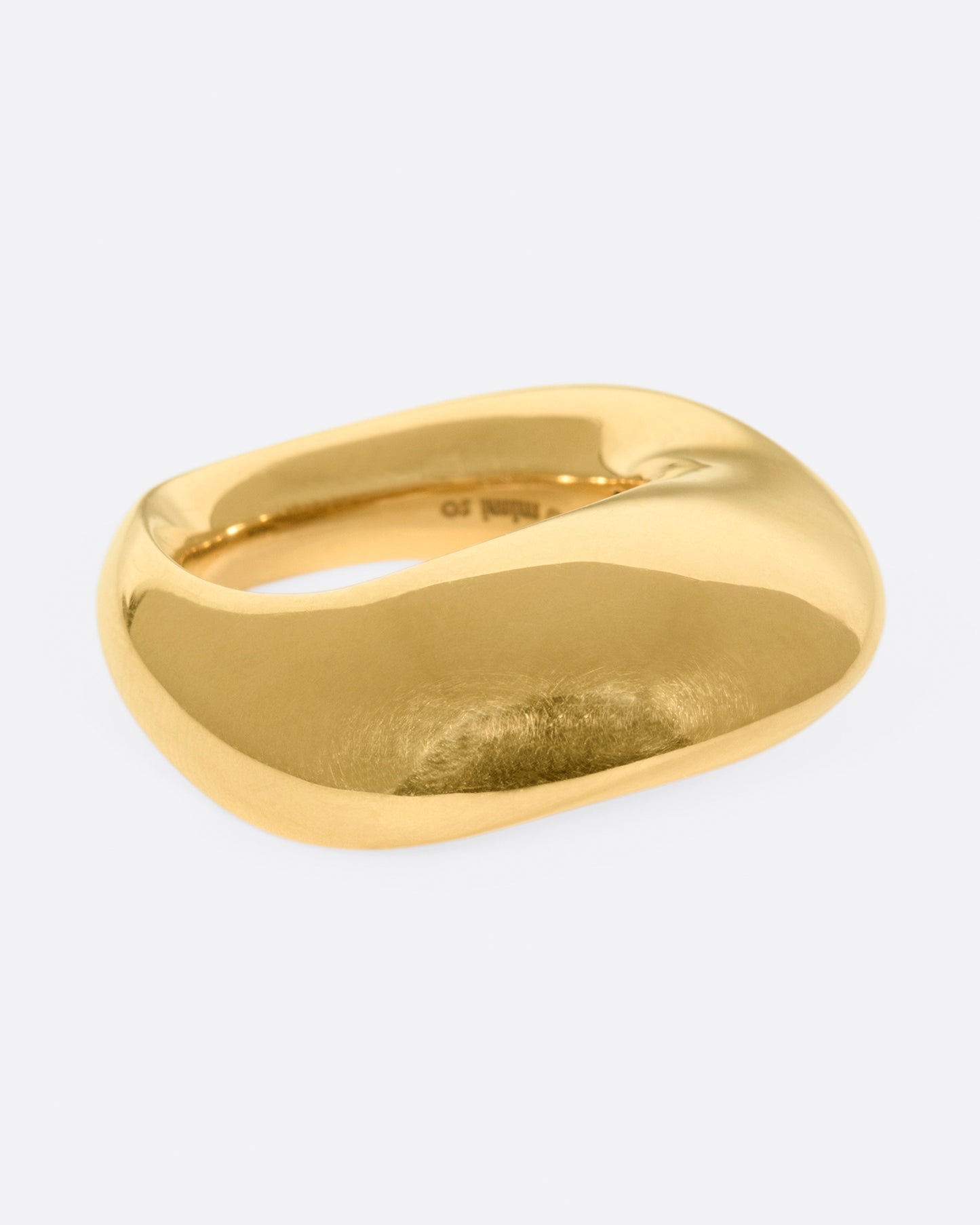 An abstract shaped gold ring with a yin yang symbol cutout on the inside of the band.