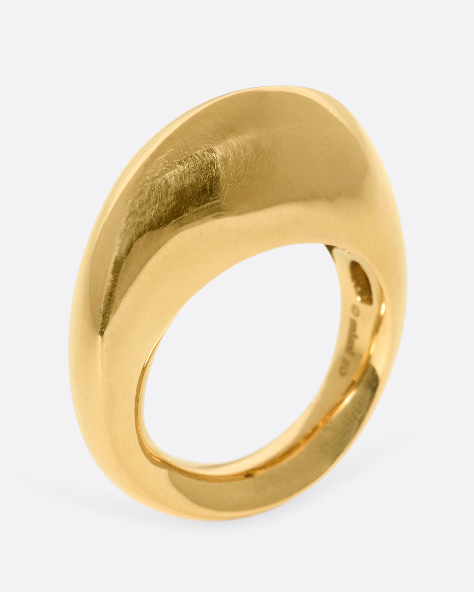 An abstract shaped gold ring with a yin yang symbol cutout on the inside of the band.
