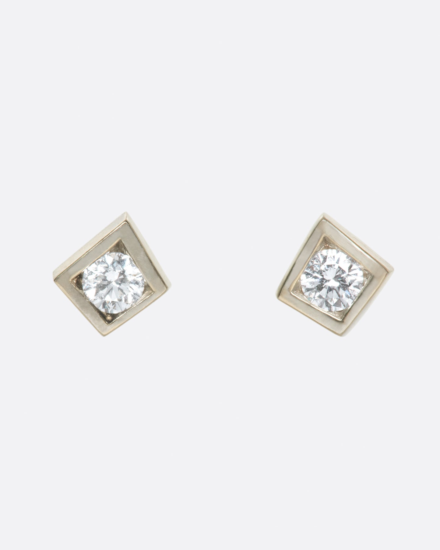 A pair of round diamond solitaire earrings with square tension settings.