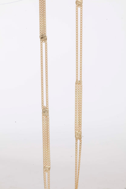 A long yellow gold multi chain necklace with alternating pattern of squares finished with gold solder. Shown close up from the front.