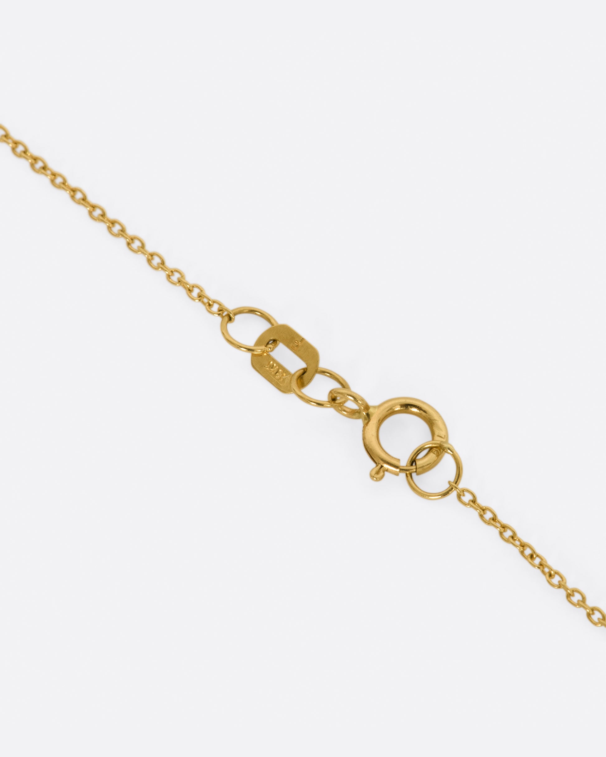 A yellow gold bar necklace with a single row of white diamonds. View of the clasp.