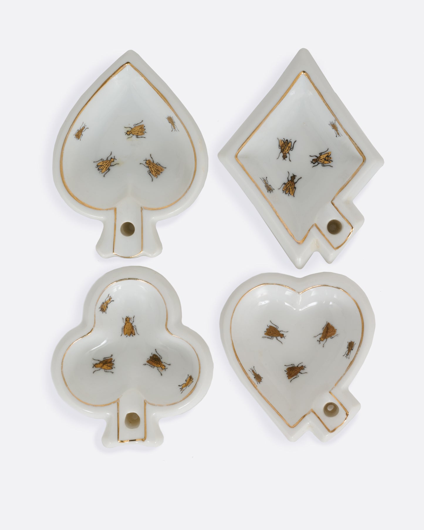 Four white ceramic dishes shaped like playing card suits with  gold trim and bug designs. Shown from the top.