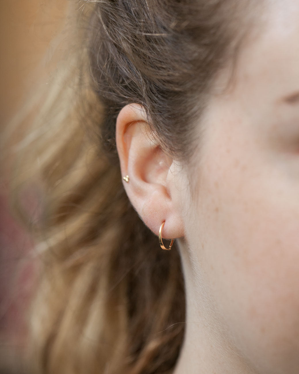 This little hoop is simple and easy to wear. It's a little larger than a snug; meaning it will not touch the ear lobe, but rather hang slightly below.