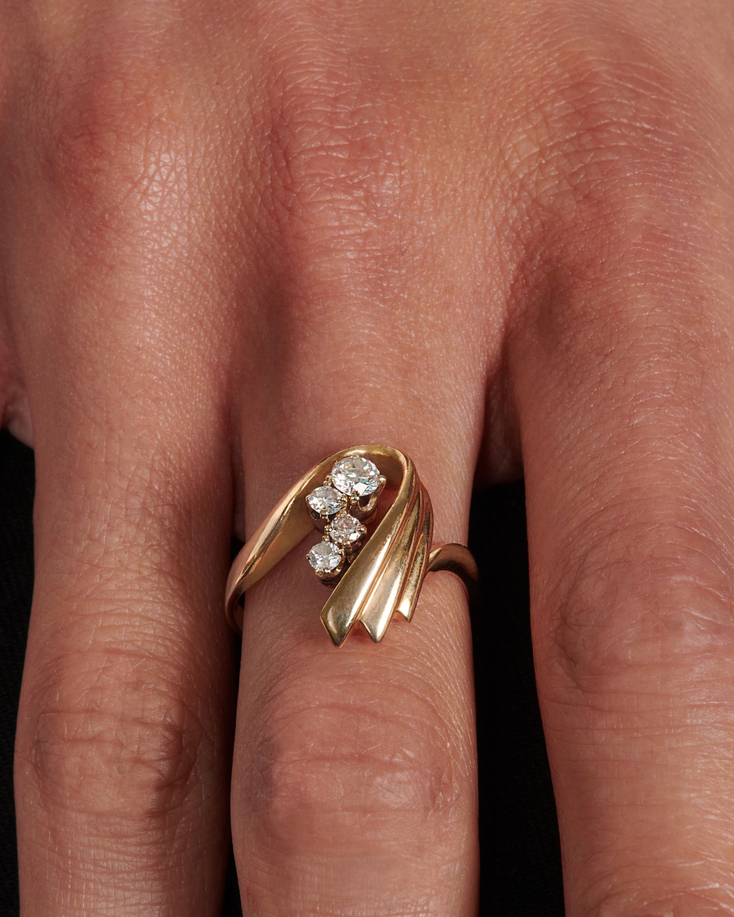 A vintage 14k gold U-shaped ring with four round diamonds resting in the center