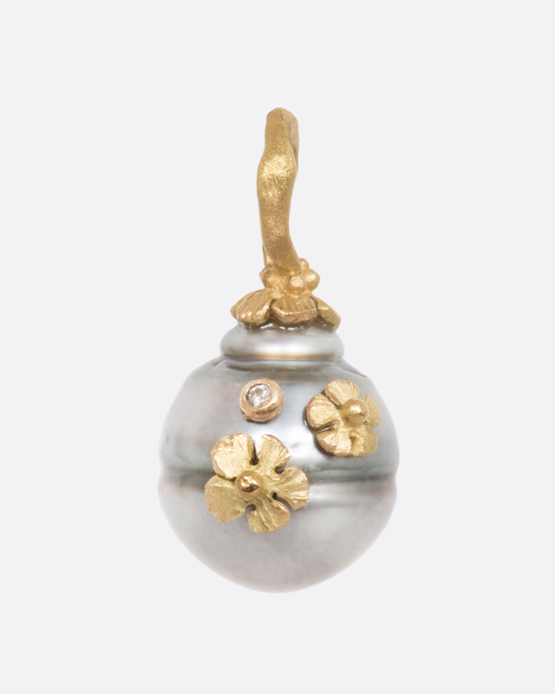 A pearl pendant with a yellow gold bale, adorned with tiny flowers and a diamond. View from the front.