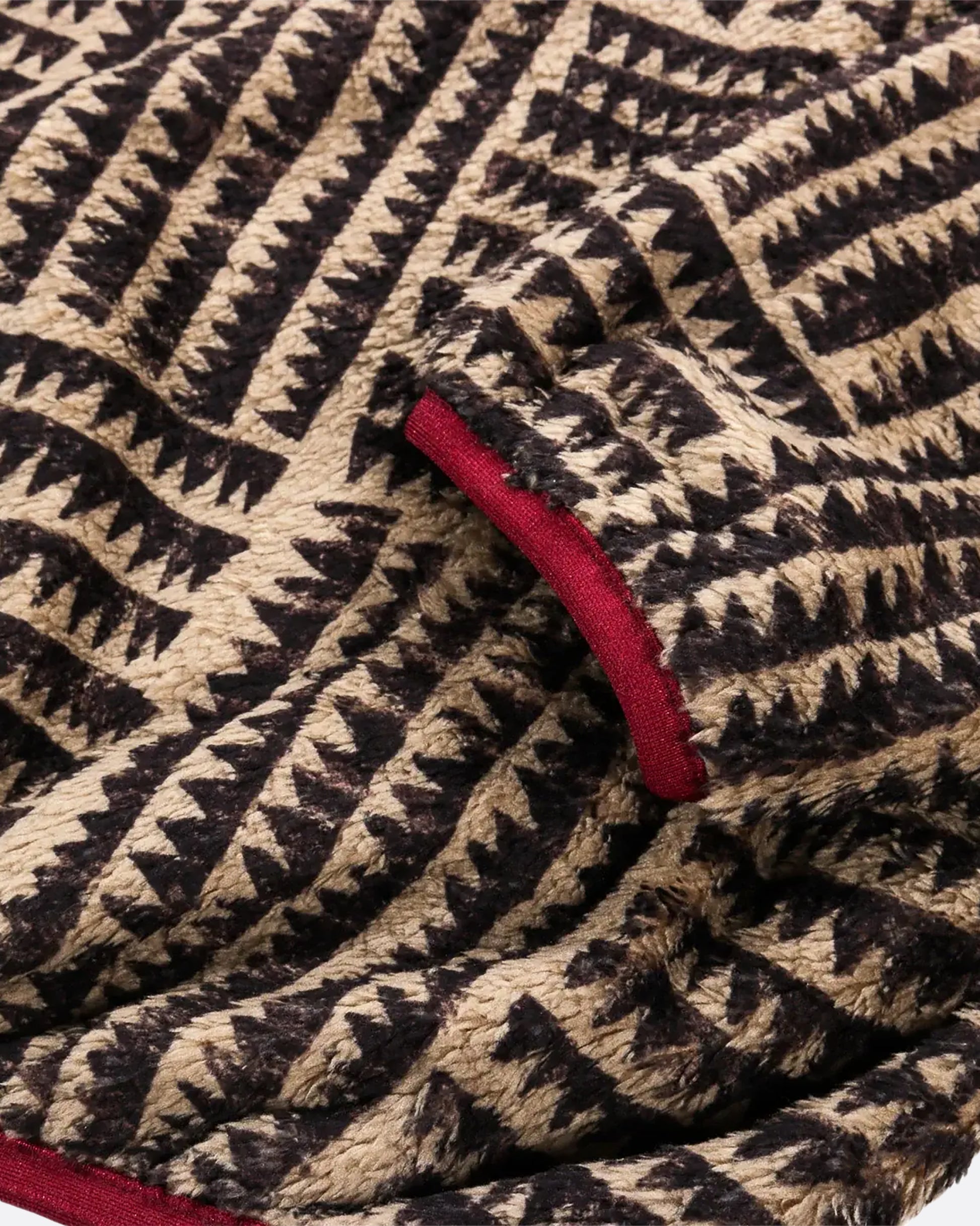 A brown a tan zig zag print fleece pullover with pink detail at the front closure. View of the cuff, close up.