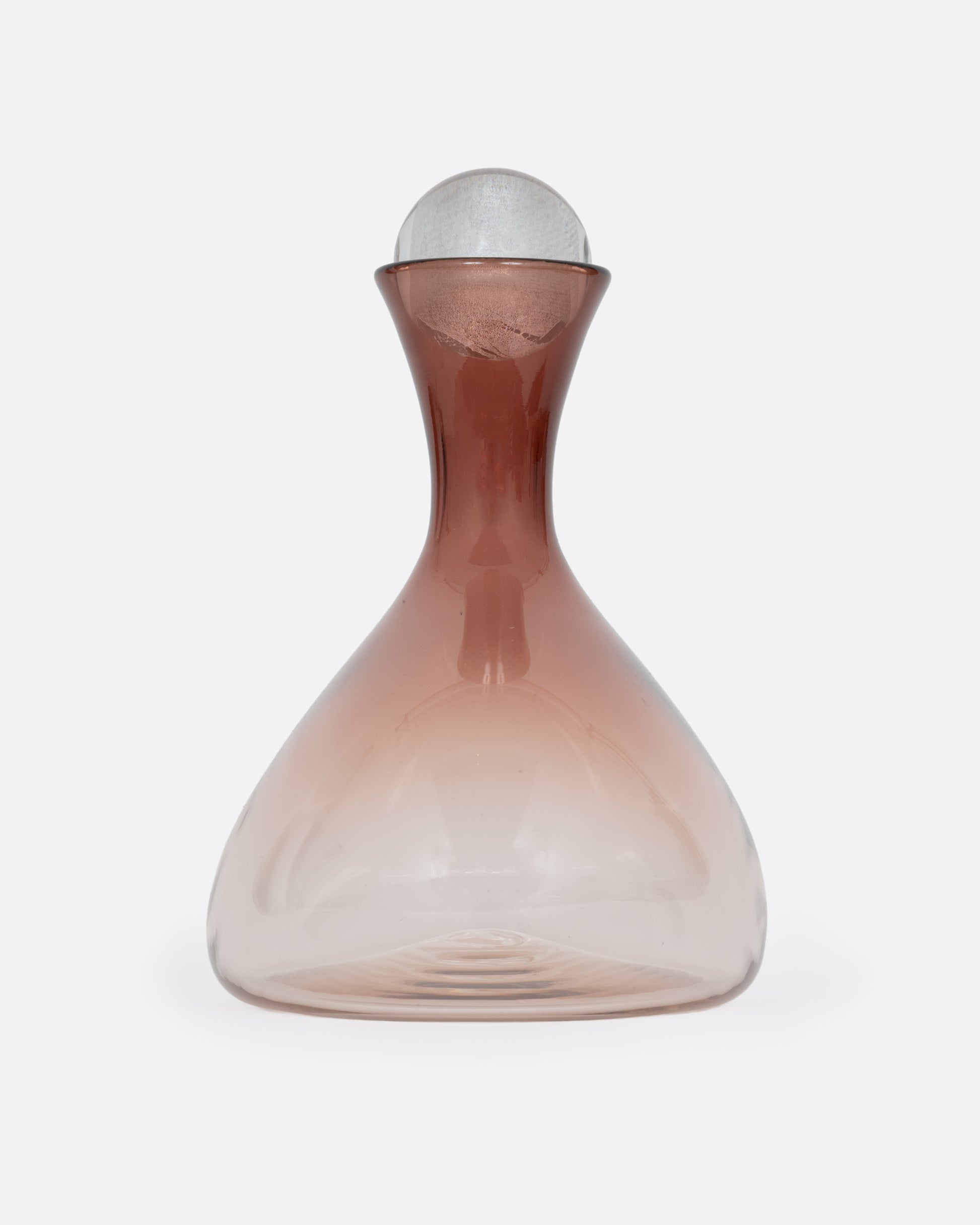 A blown glass decanter in an aubergine gradient with a wide base and a round silver stopper, shown from the side.