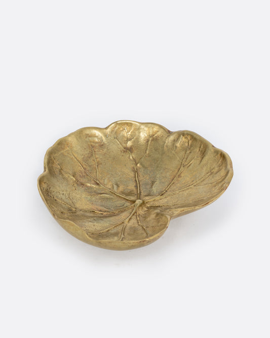 A brass leaf shaped dish, shown from the side.