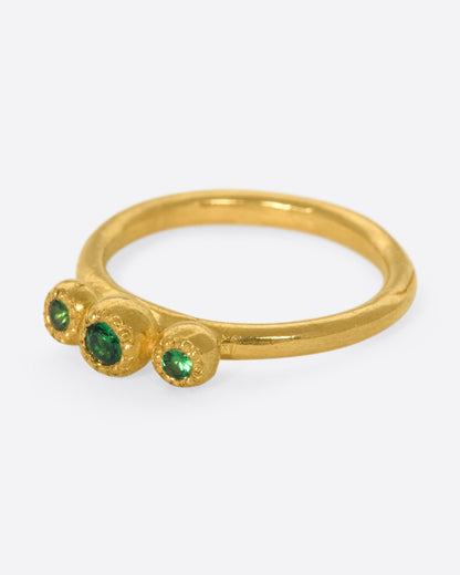 Yellow gold green garnet three stone ring, side view with the stones facing left