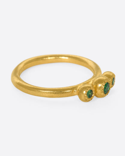 Yellow gold green garnet three stone ring, side view with the stones facing right