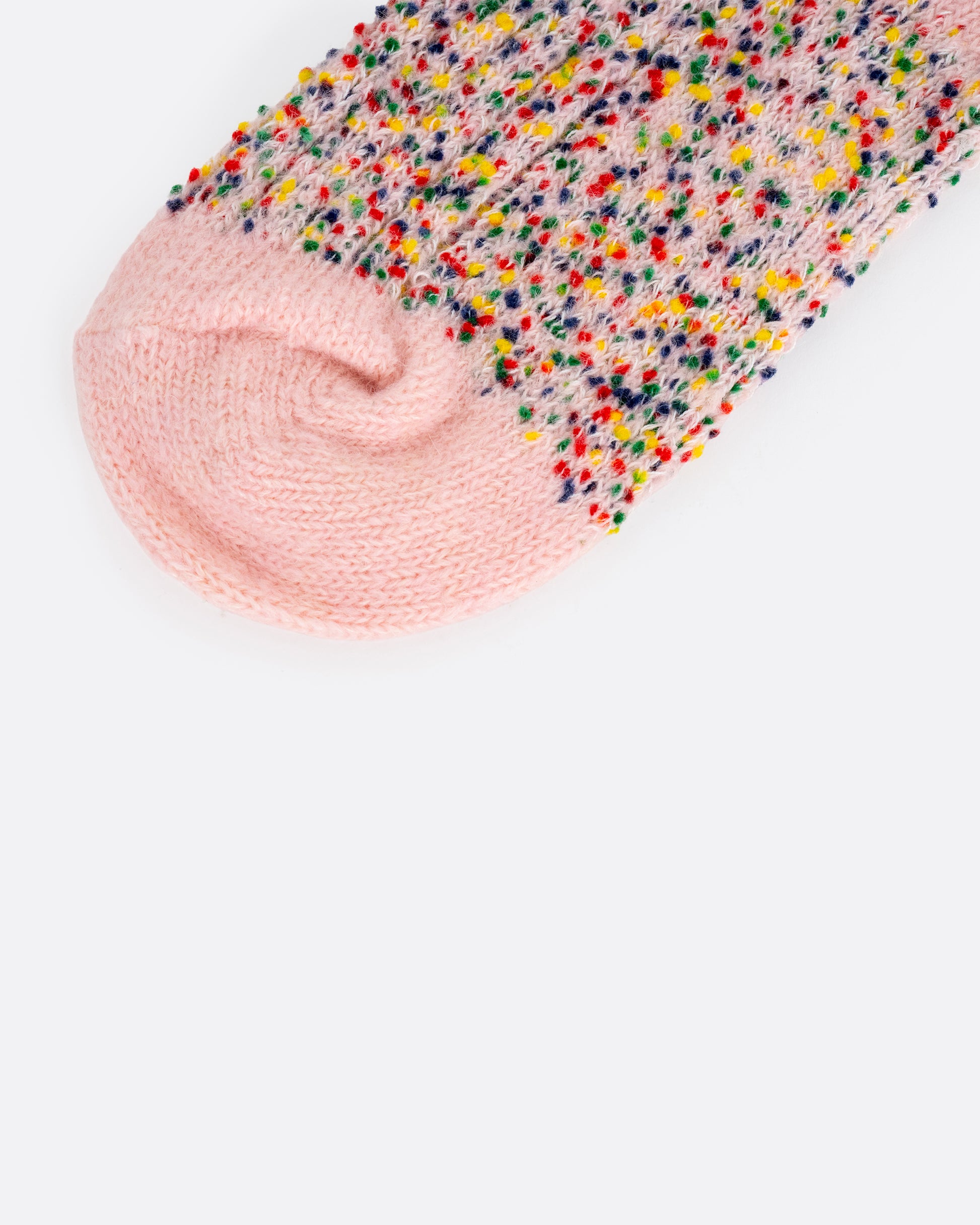A close up of a pink crew sock with colorful confetti yarns.